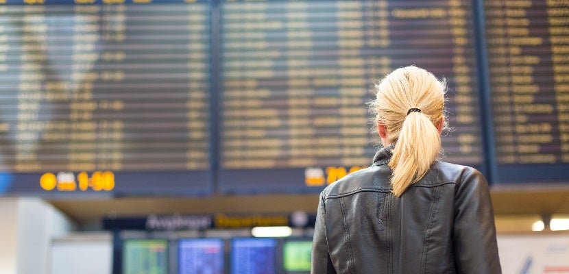 Female traveller checking flight departures board.