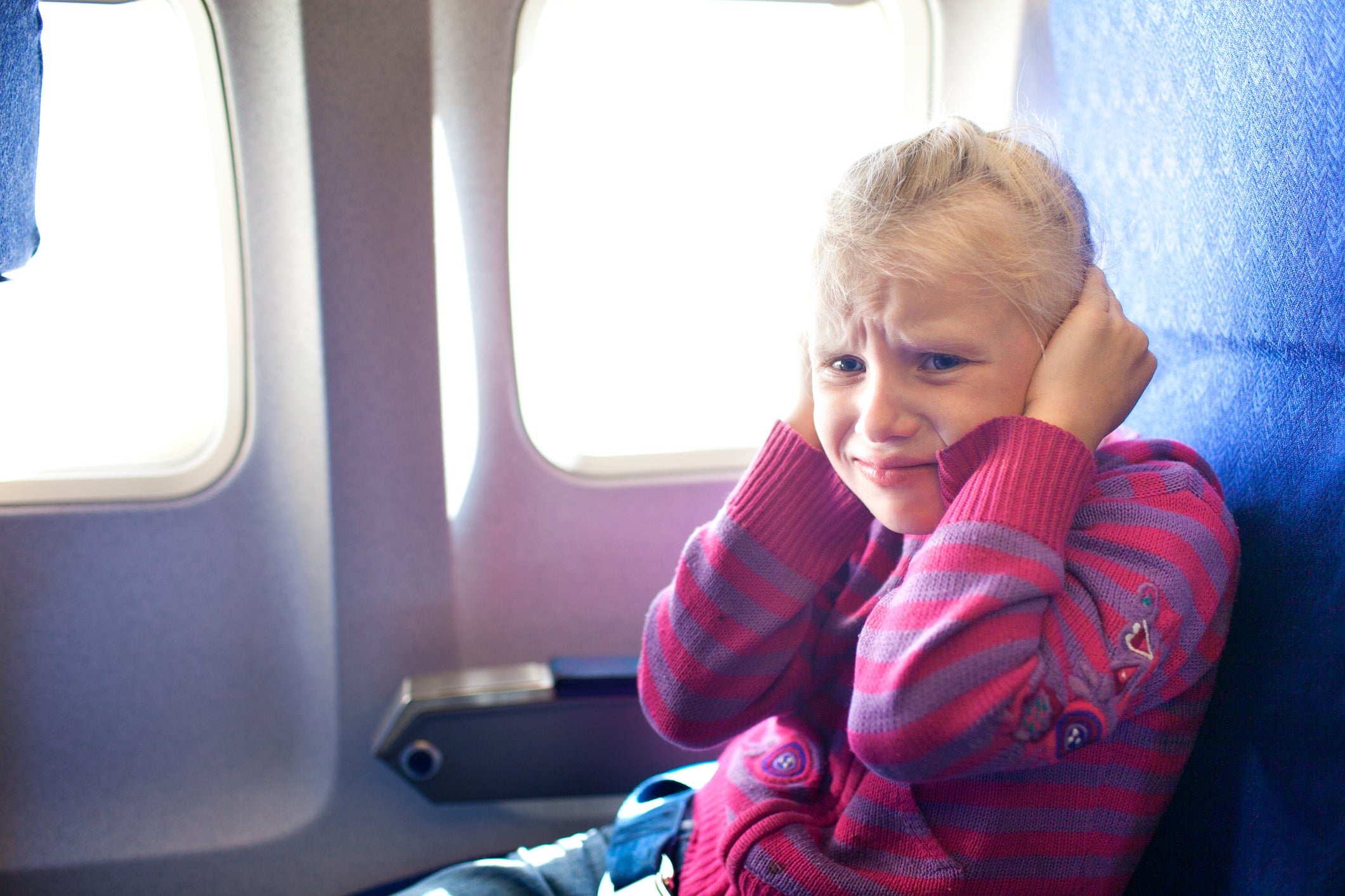 girl closing ears in the airplane