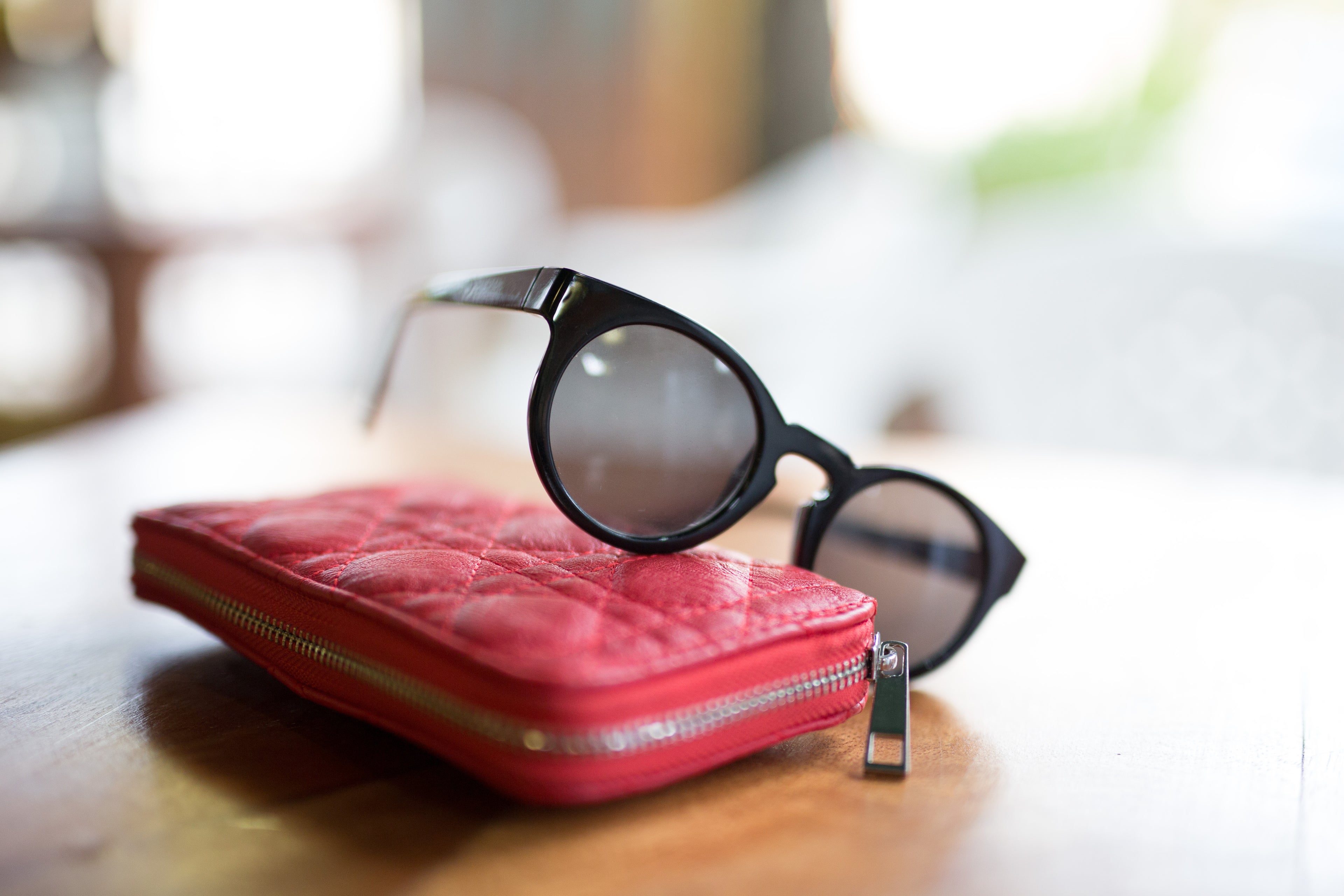 Close-Up Of Sunglasses With Purse On Table At Home