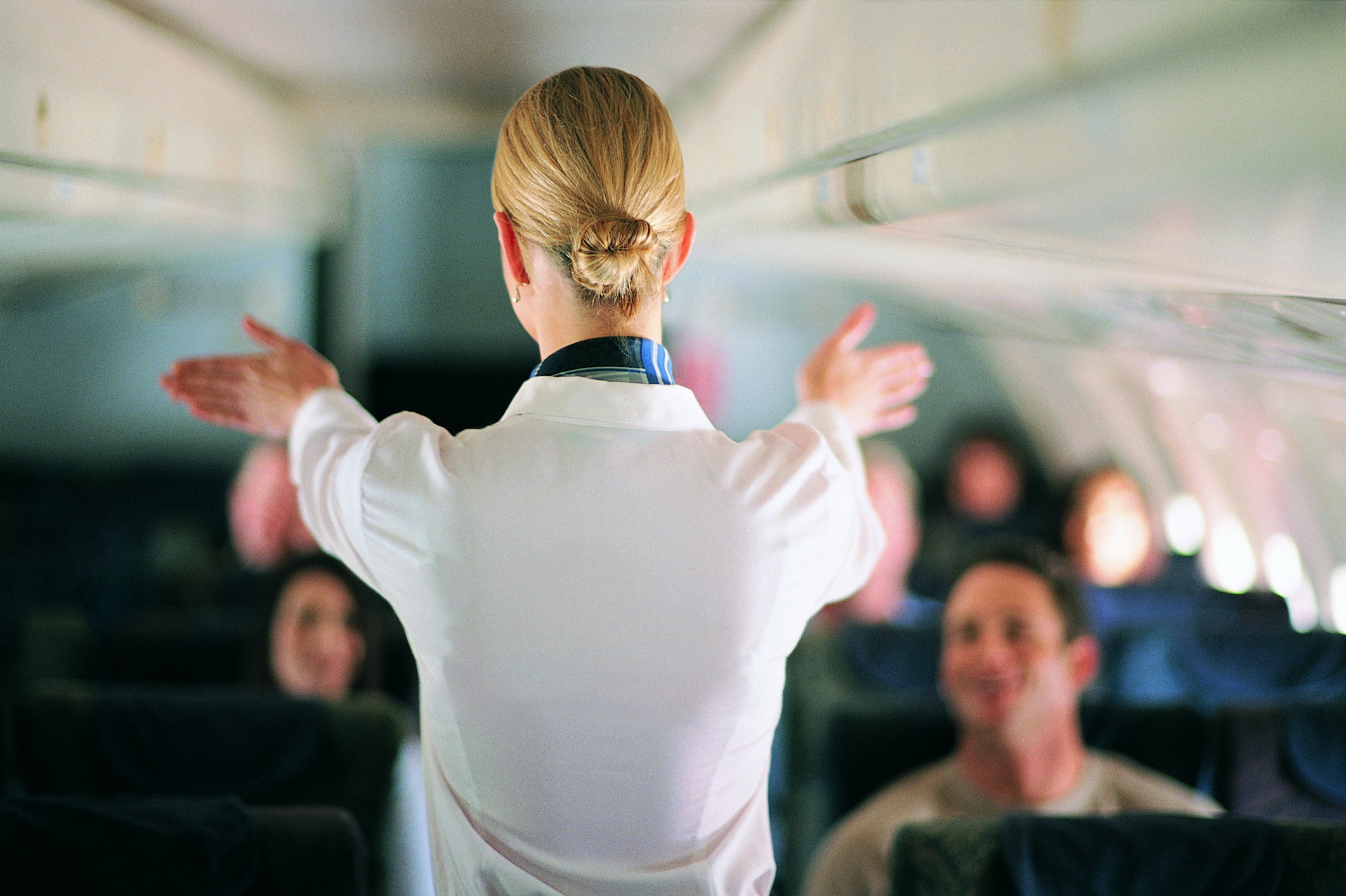 Rear View of Air Stewardess Explaining Aeroplane Safety to Passengers