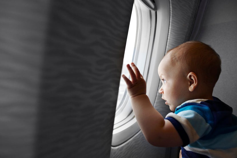 Baby boy looking fascinated out of airplane window