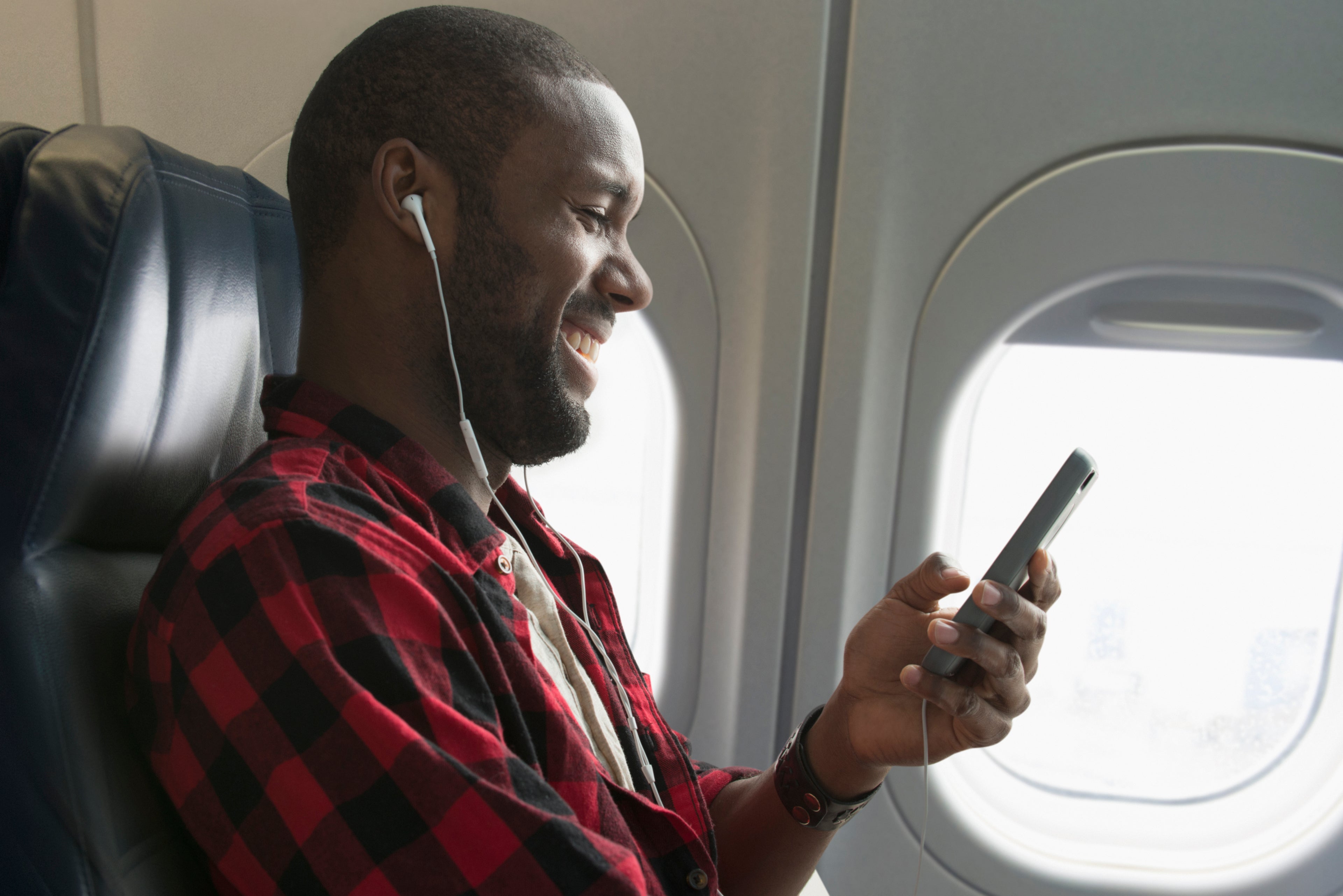 Black man listening to earbuds on airplane