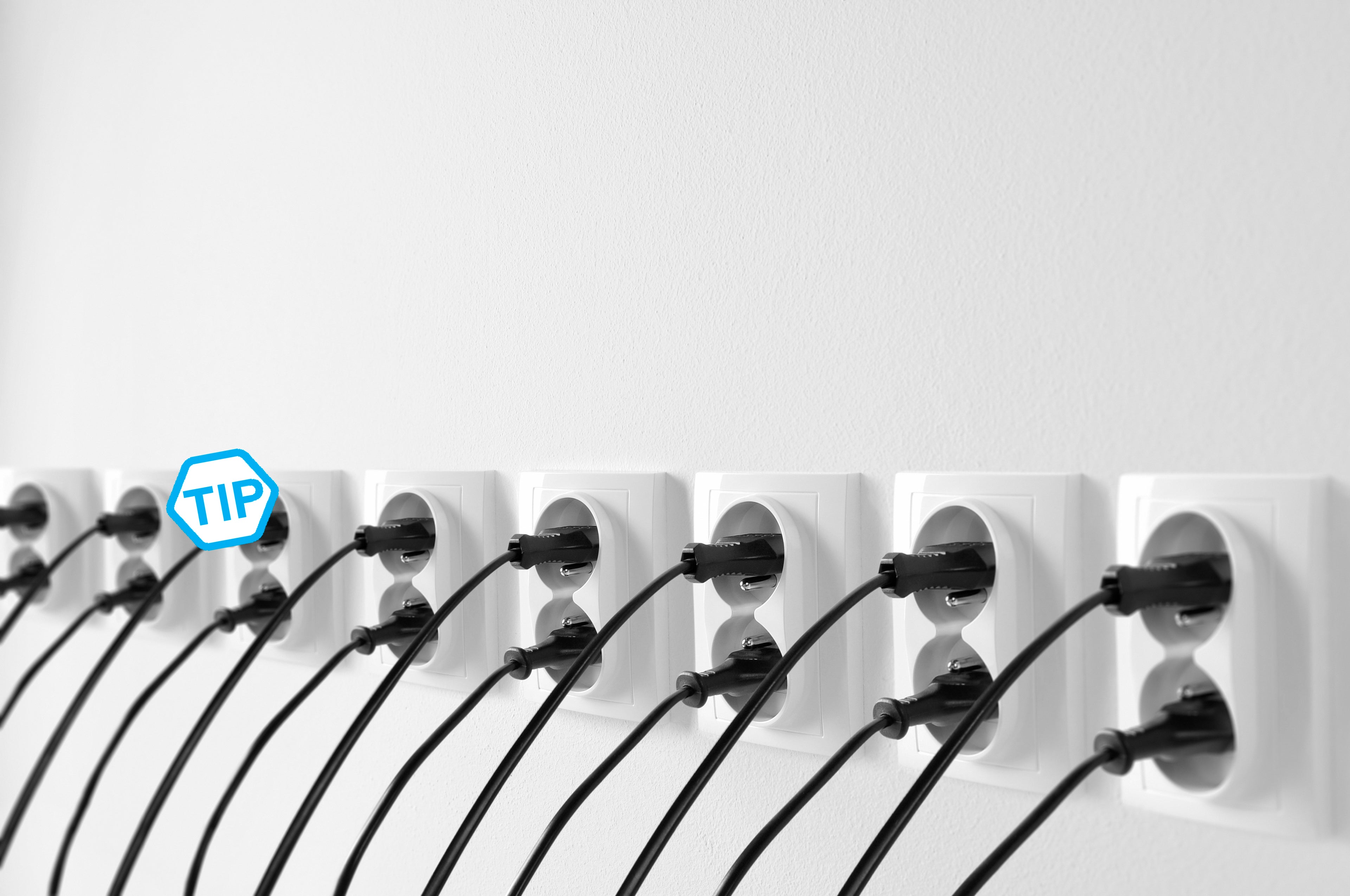 Group of wall outlets with black plugs, cables stucked in