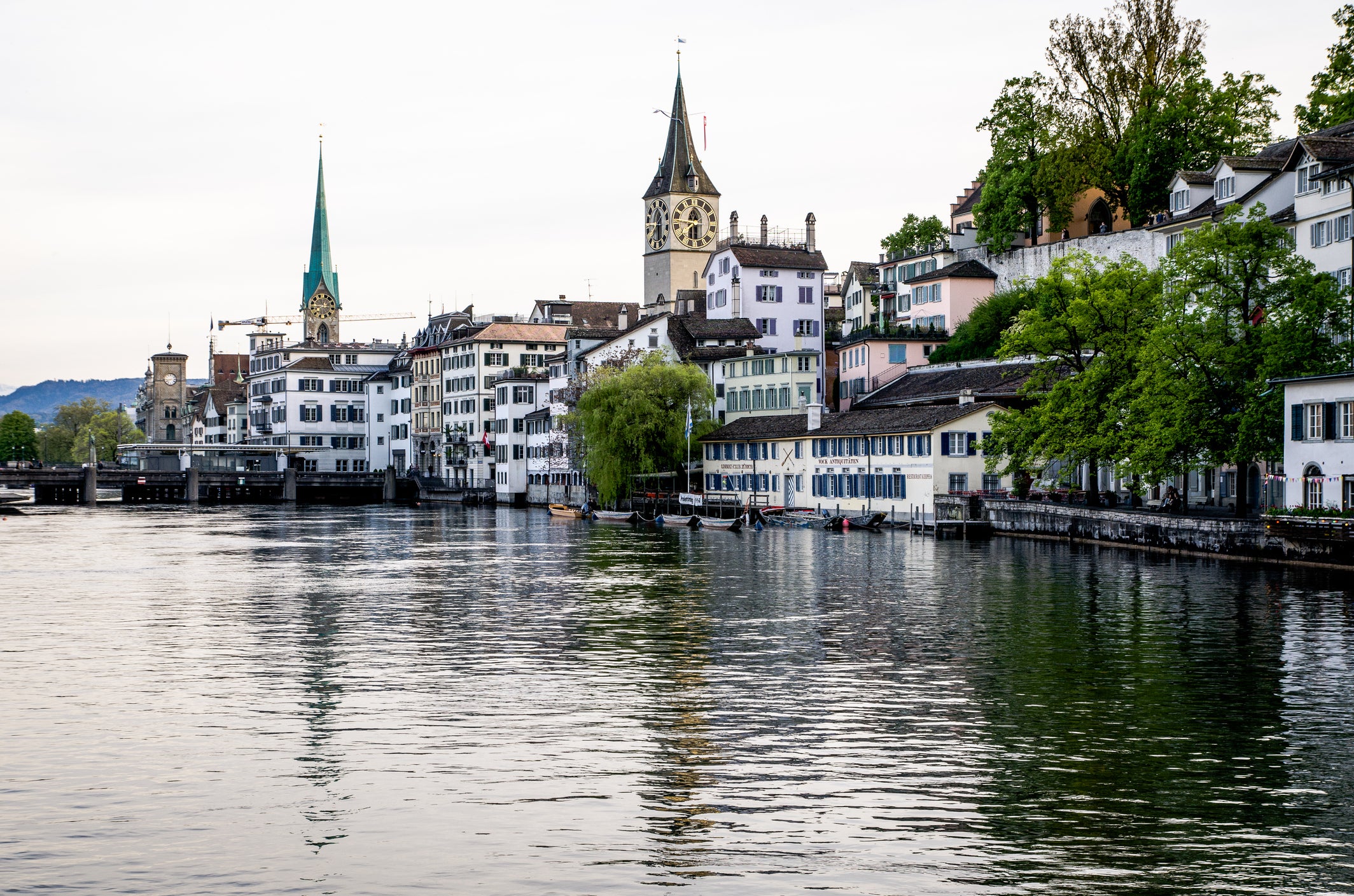 Churches And Buildings By Limmat River In City Against Clear Sky
