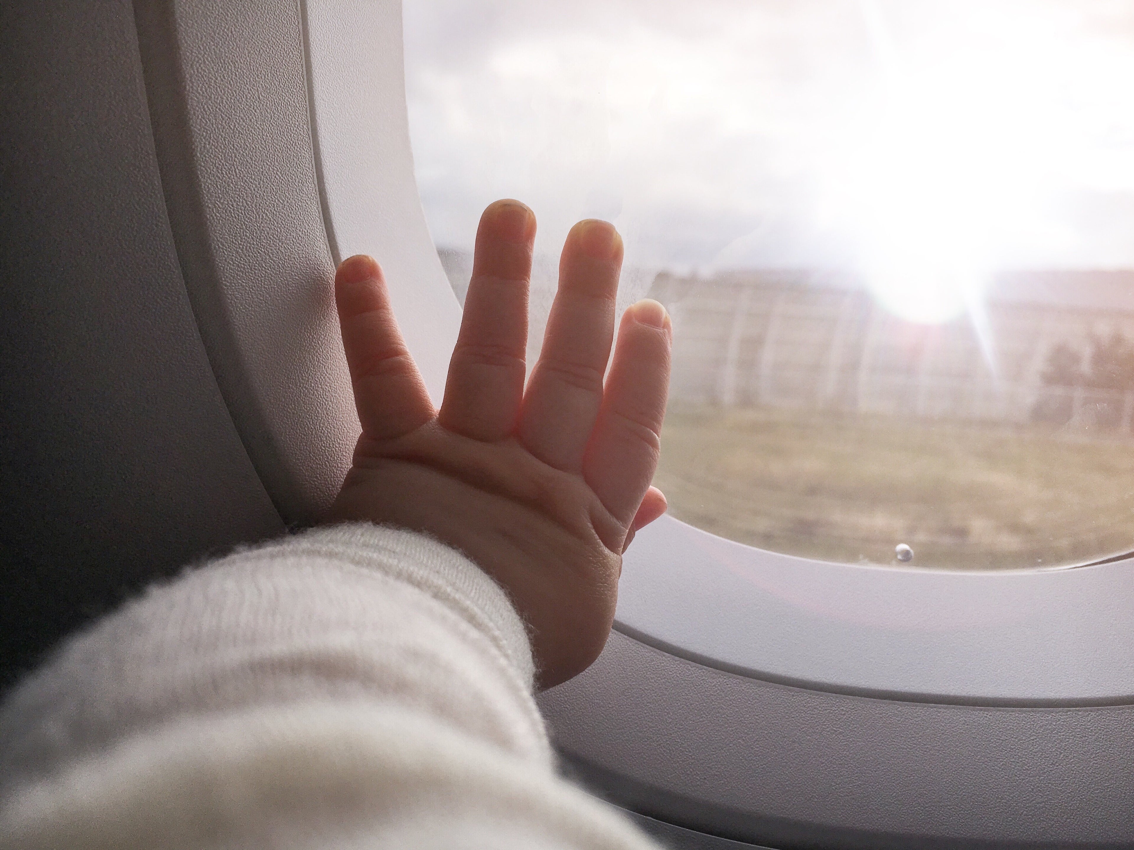 Cropped Image Of Baby Touching Window In Airplane