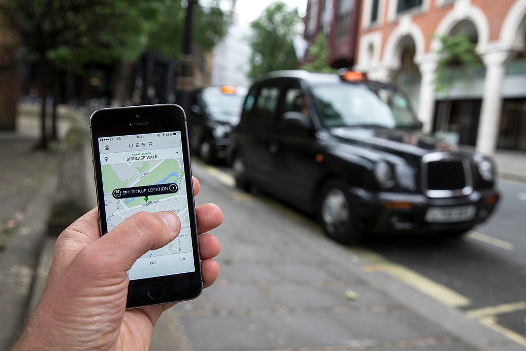 A phone shows the Uber app while a tax sits nearby