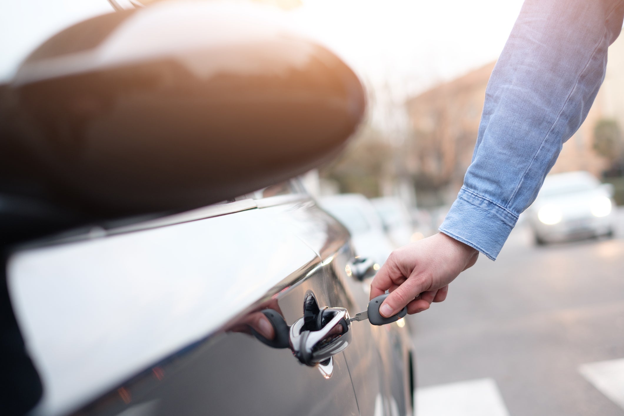 Hand holding a car key and opening the car door