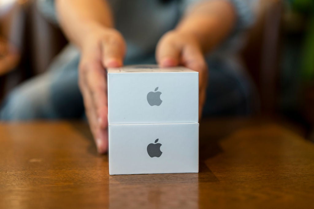 An unseen person opens an Apple iPhone box