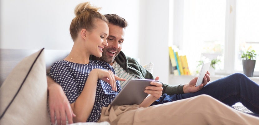 Couple lying on the bed, using a digital tablet together