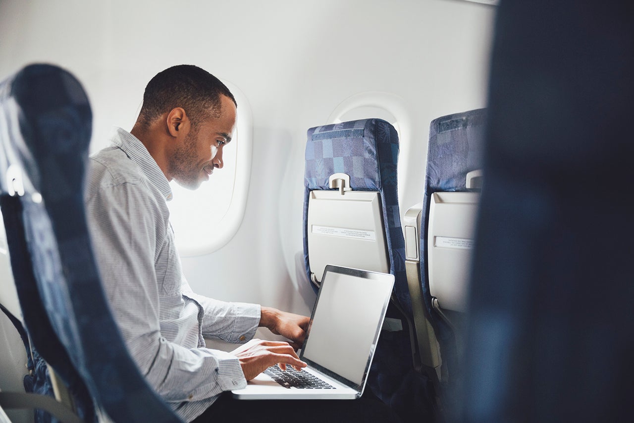 Man using laptop in airplane