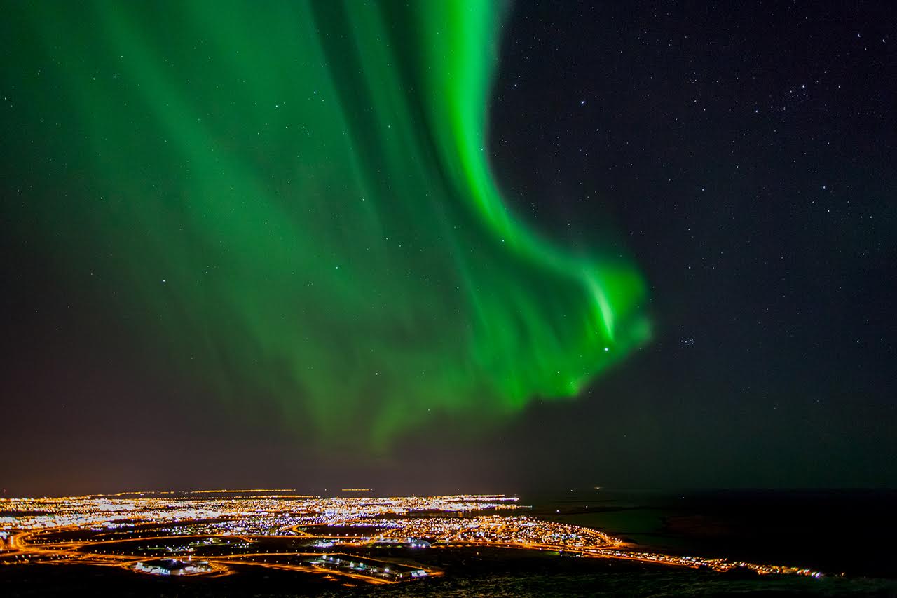 view of northern lights (aurora borealis) over a city