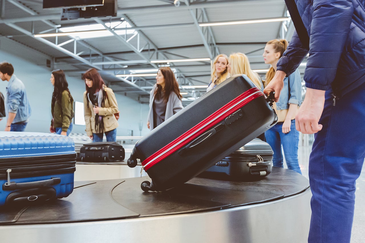 Airplane travelers waiting for luggage near conveyor belt