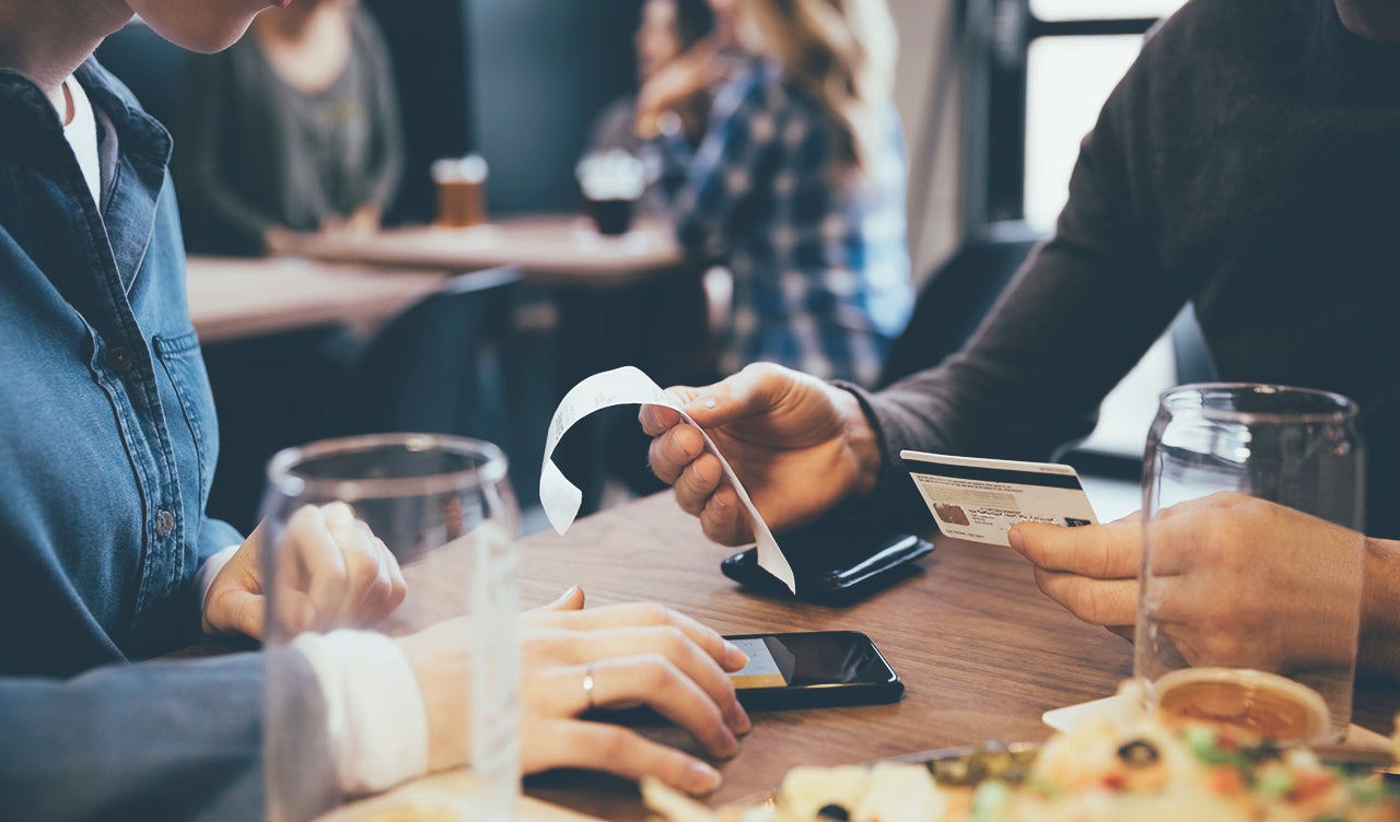 Close up couple with credit card paying bill calculating tip with smart phone in brewery restaurant