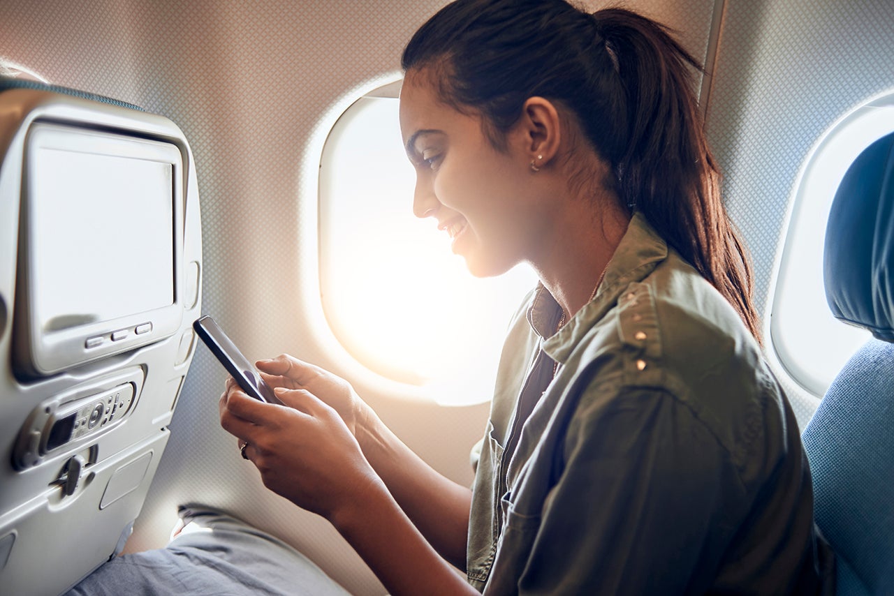 woman using her smartphone in the plane