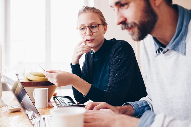 Side view of couple shopping online from laptop at home