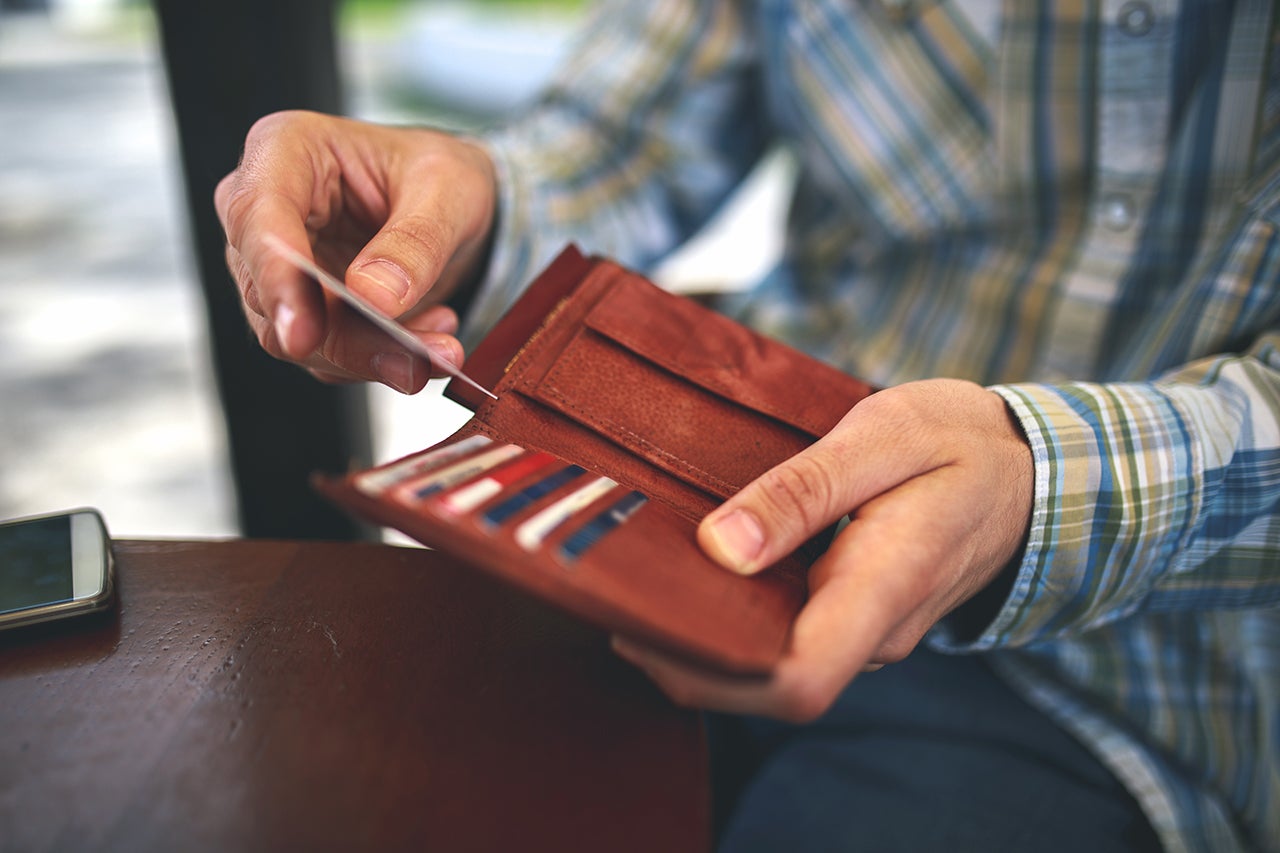 A person holds a wallet while pulling out a credit card