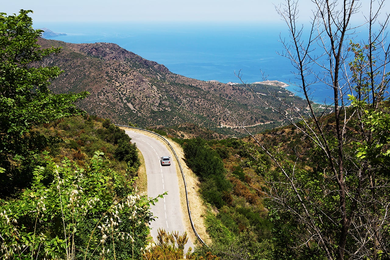 One car on the curvy road in the mountains of catalonia with mediterranean sea in the background (near Porta de la Selva, Catalonia/ Spain)