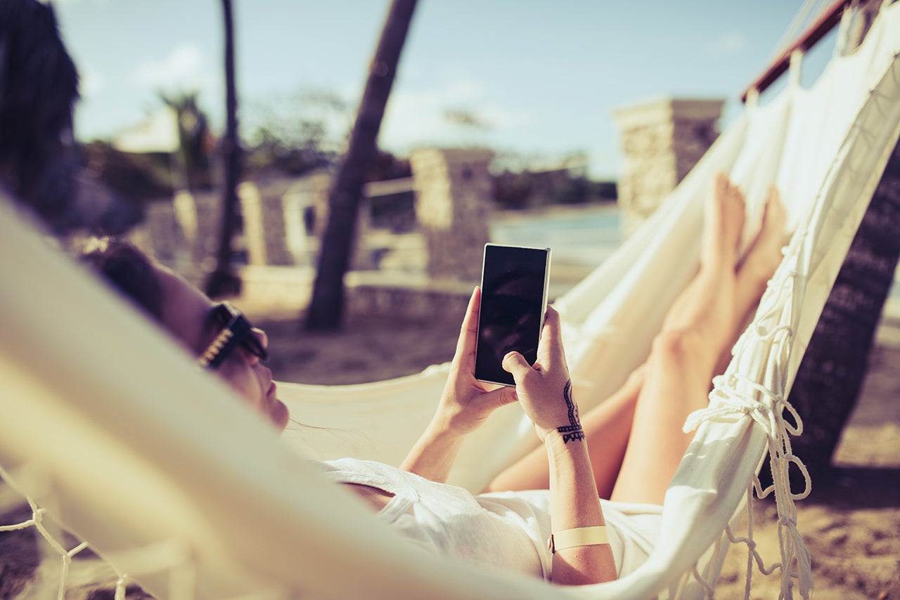 Woman using her phone while relaxing in a hammock