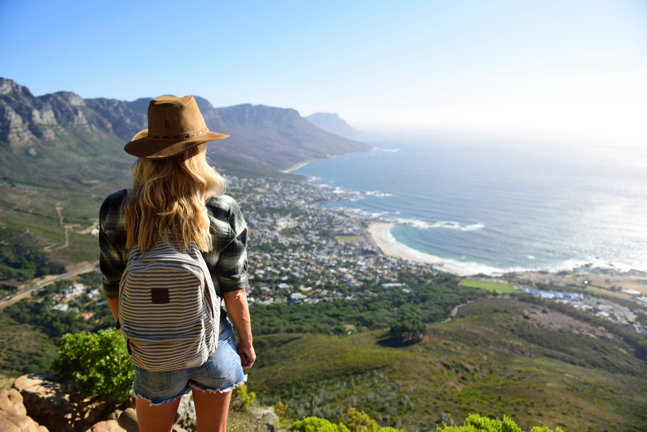 South Africa, Cape Town, woman standing looking at the coast during hiking trip to Lions Head