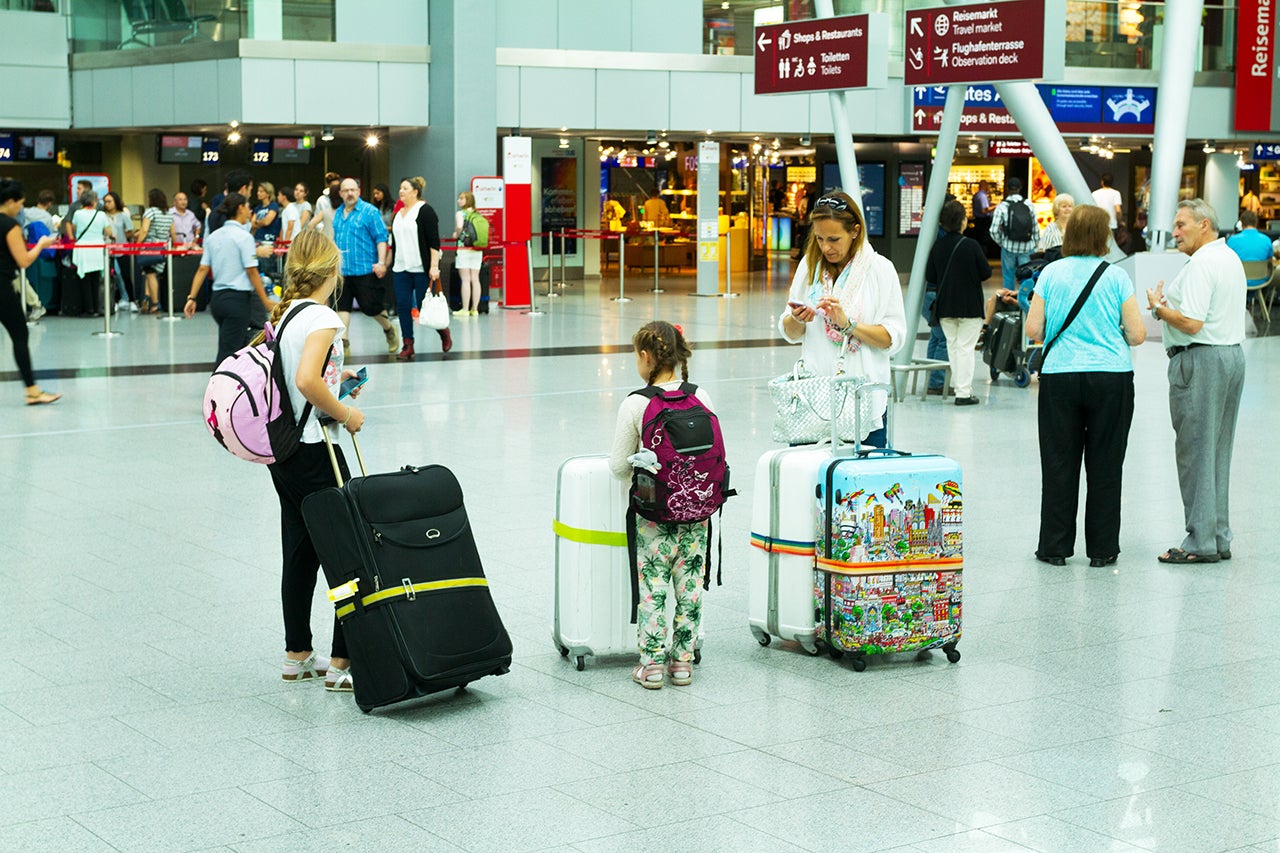 Woman with children and luggage in hall of airport Düsseldorf