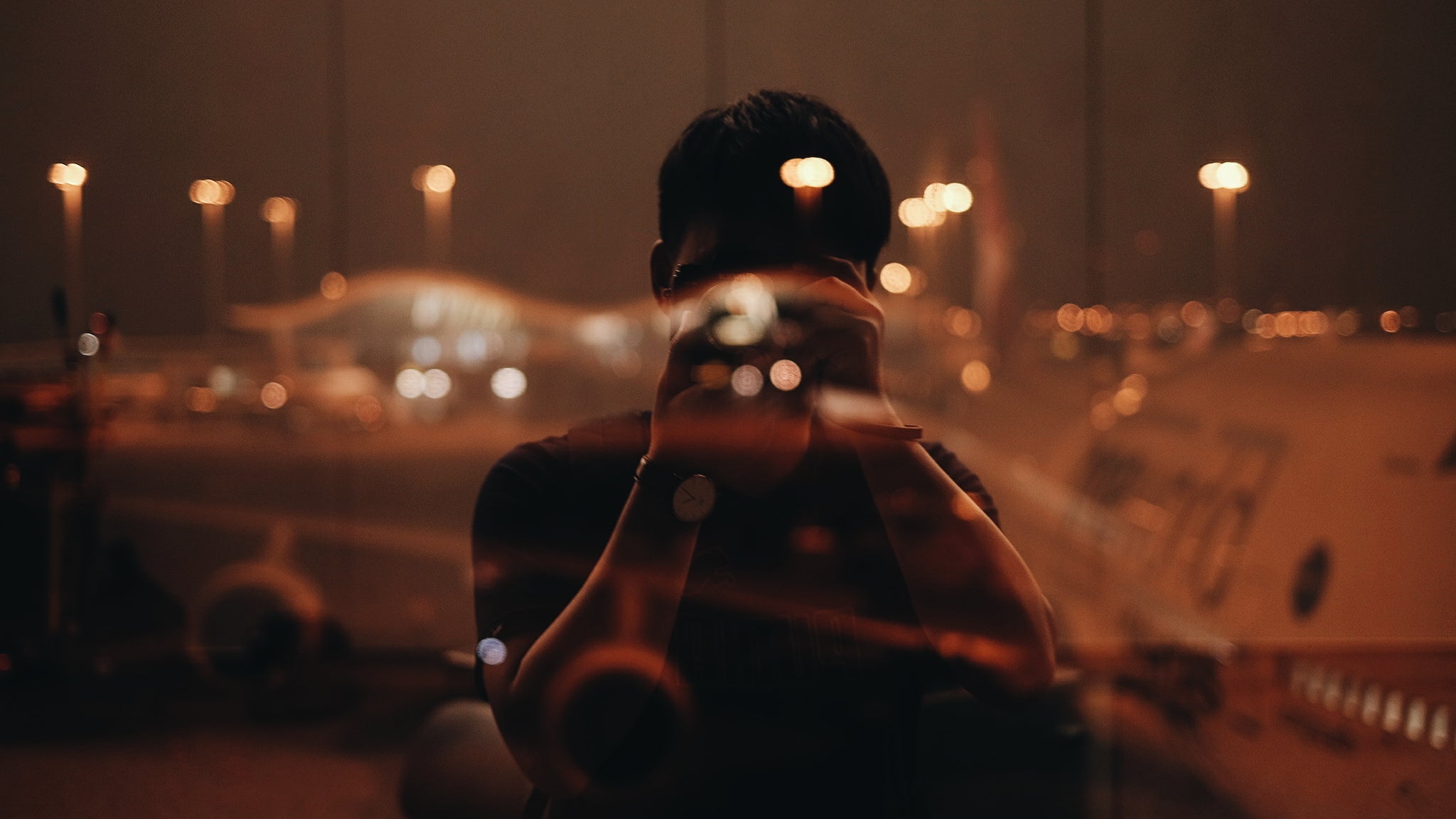 Man Photographing Through Camera Reflecting On Window At Night