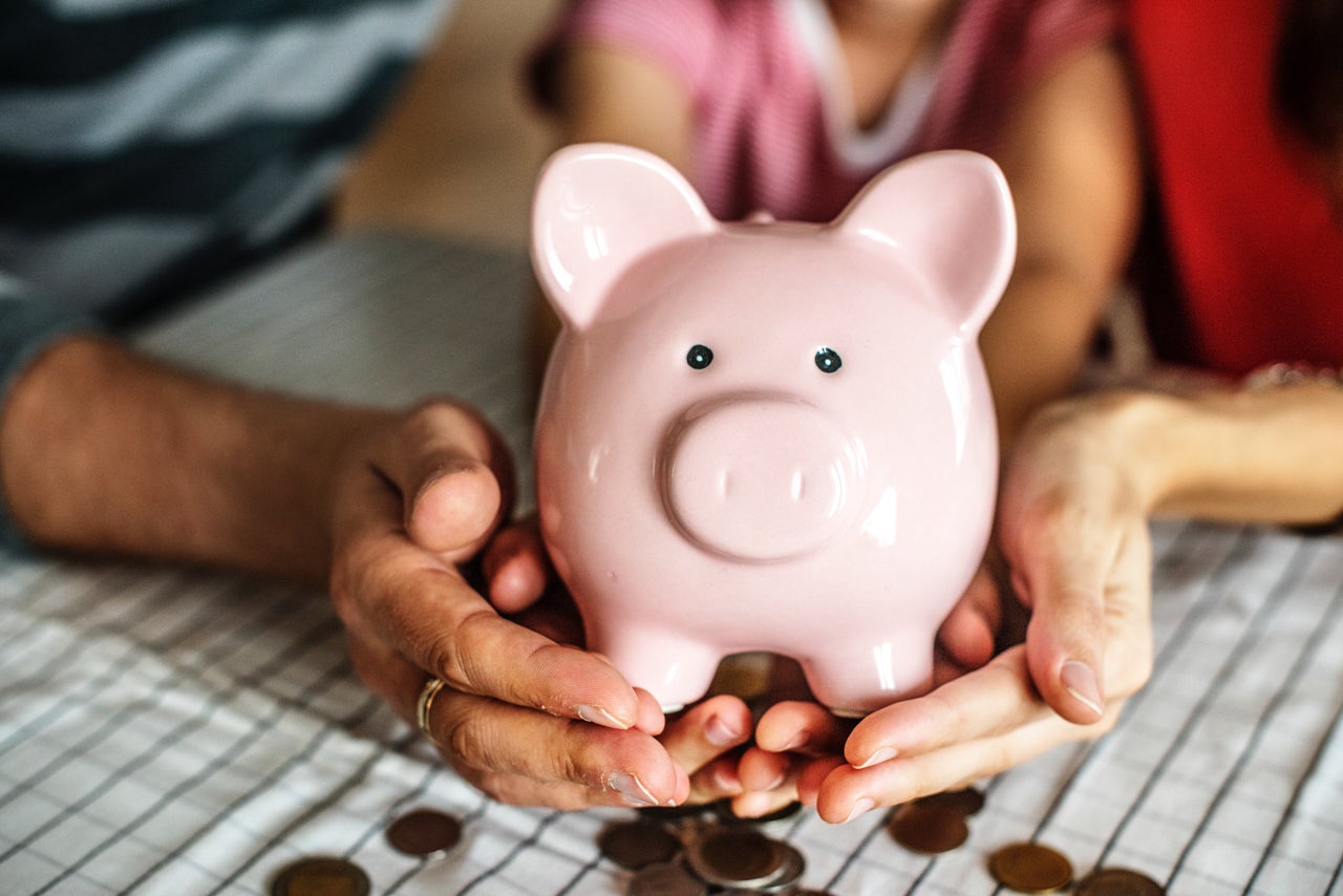 Hands are catching coins coming out of a piggy bank