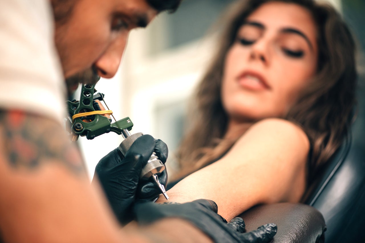 Close-Up Of Mam Making Tattoo On Woman Hand