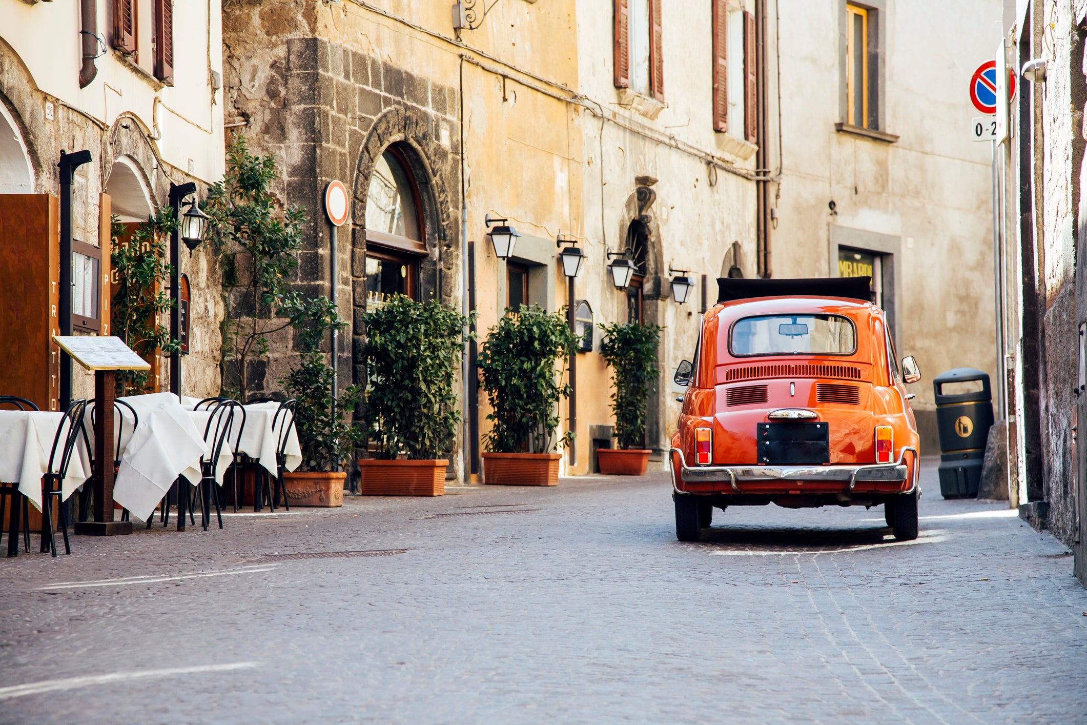 Old red vintage car on the narrow street in Italy