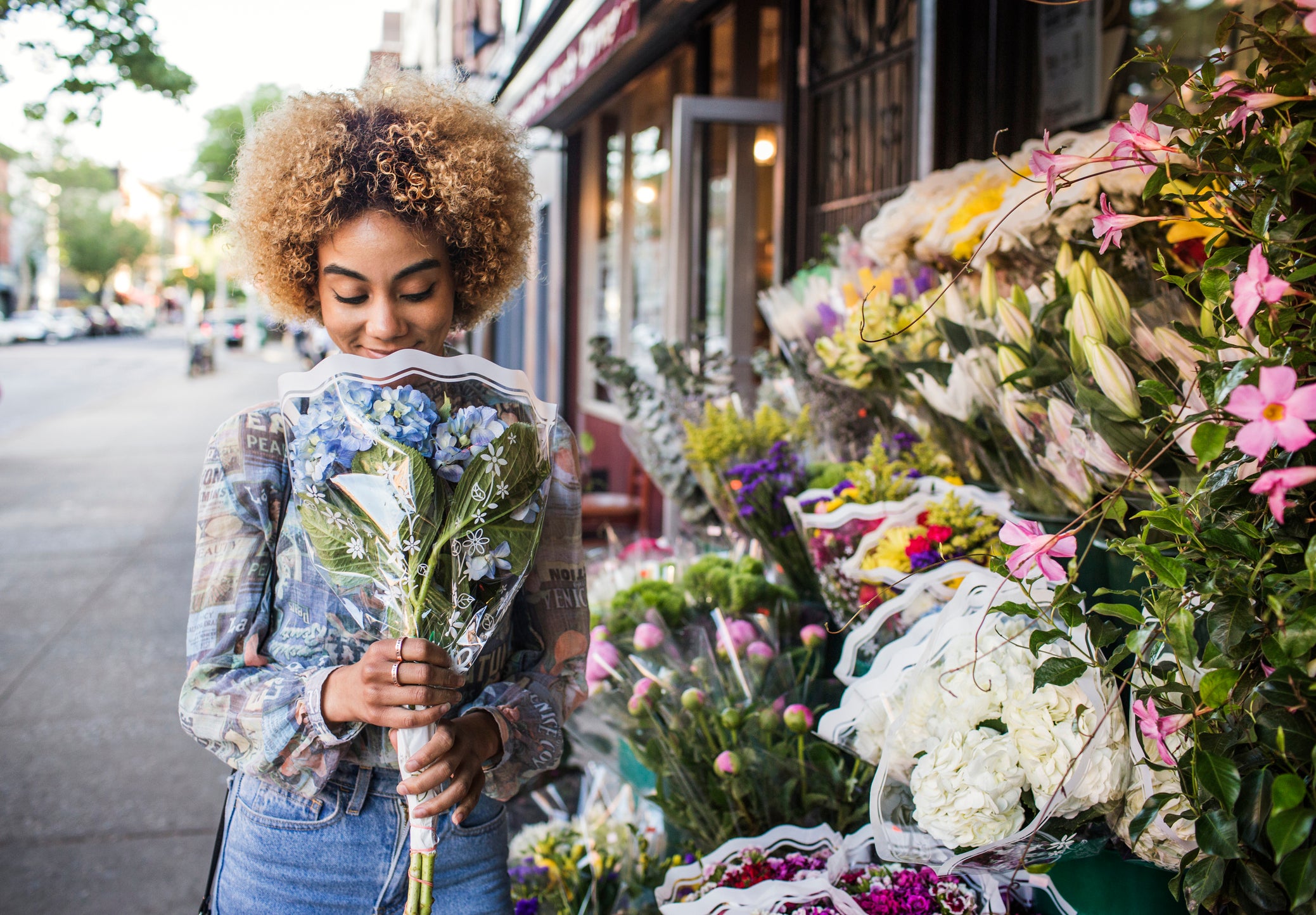 Smiling woman smelling hydrangeas outside flower shop
