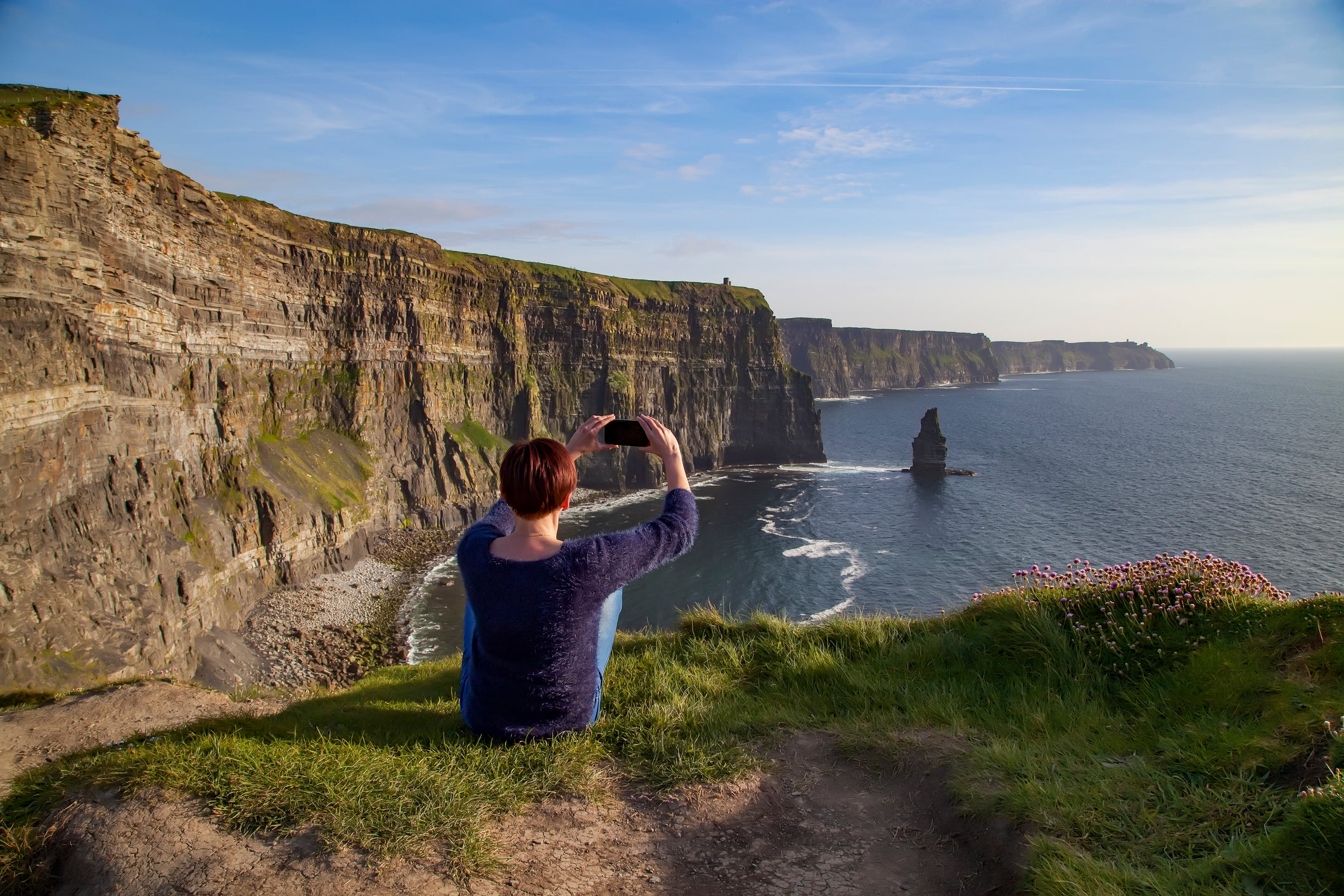 Woman taking picture of Of Cliffs Of Moher, Liscannor, Ireland and sea