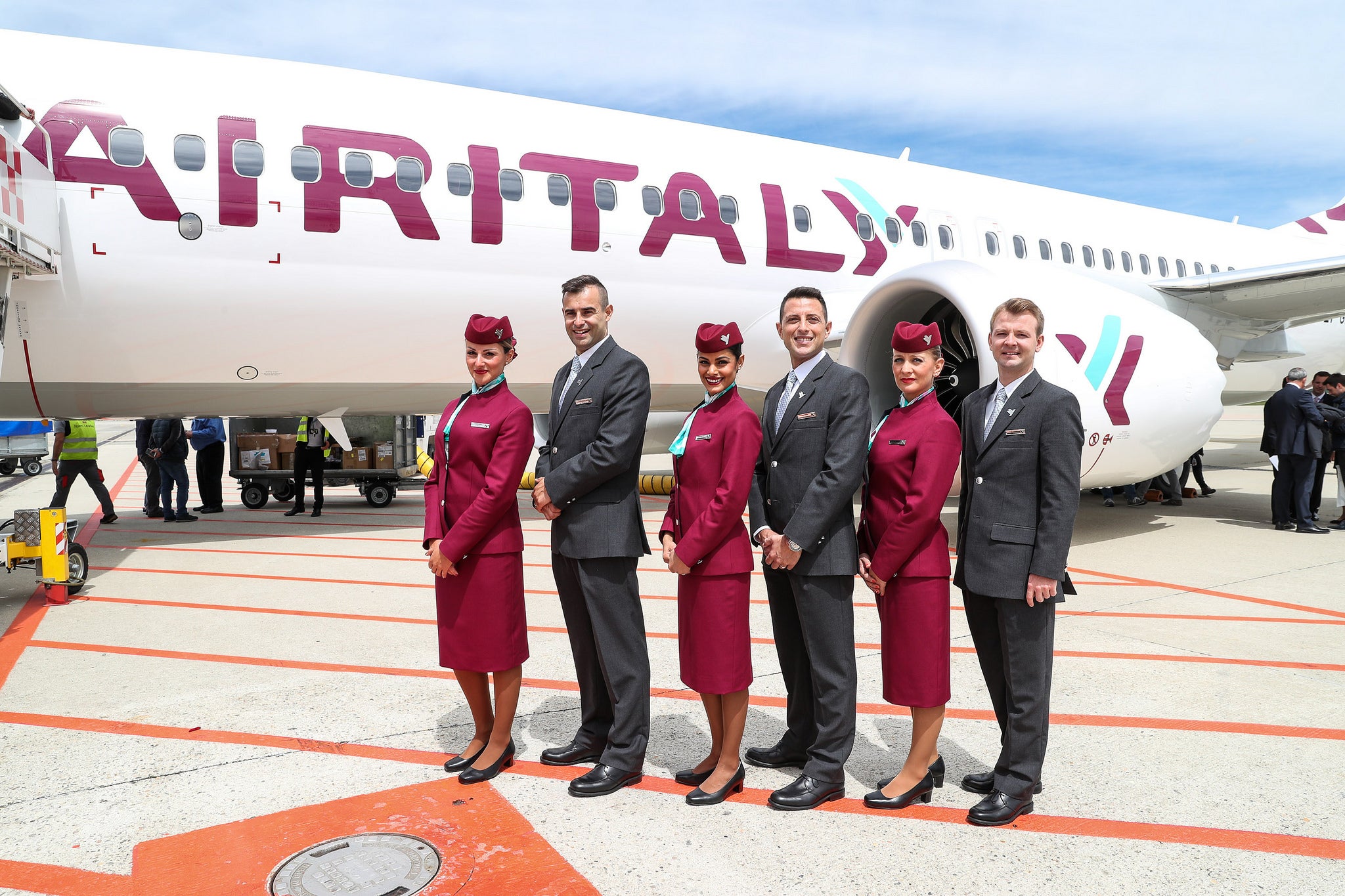 Air Italy crew members pose in front of an Air Italy aircraft.