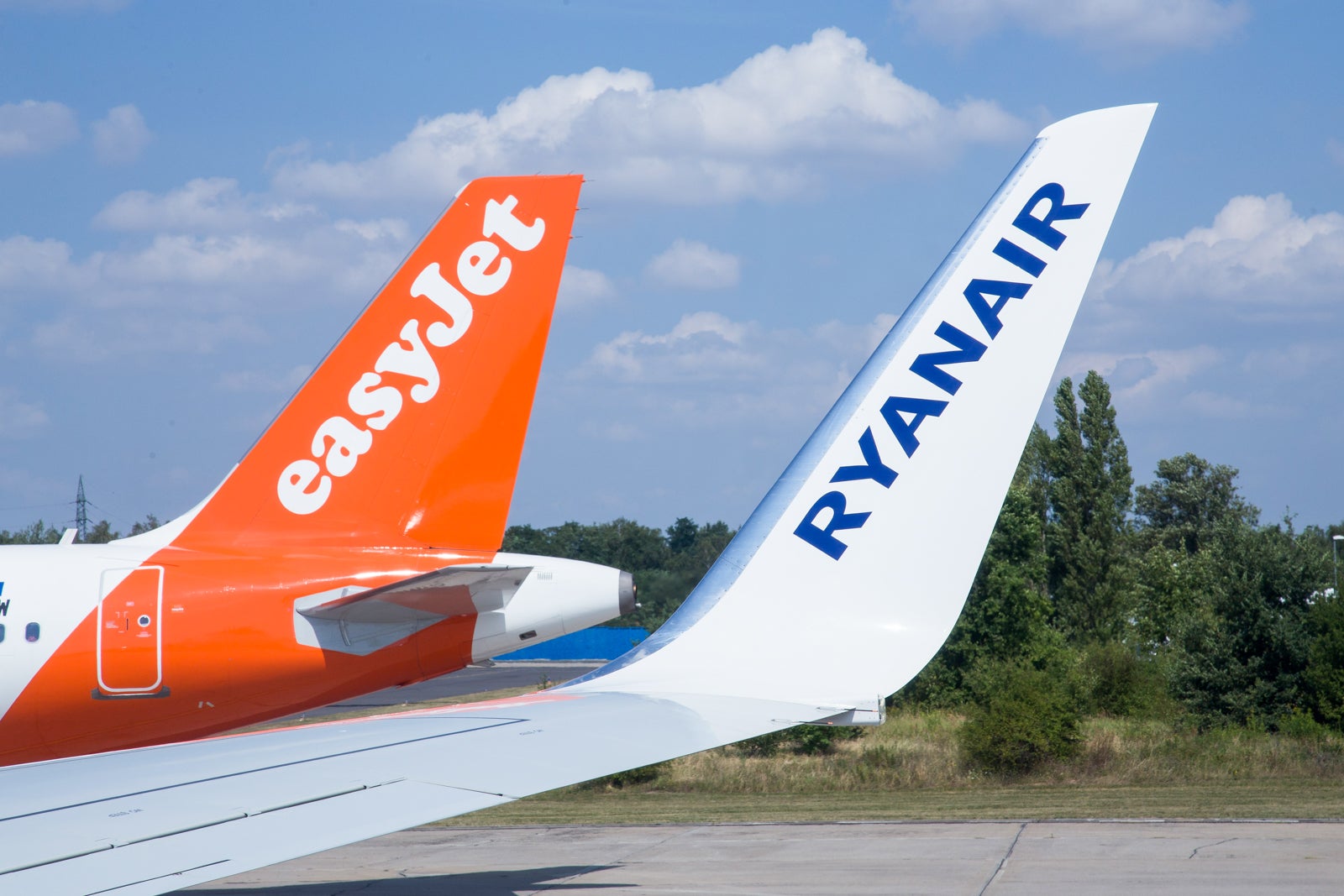 Airplane tail of Ryanair and Eesy Jet lowcost airlanes standing side by side at the airport.