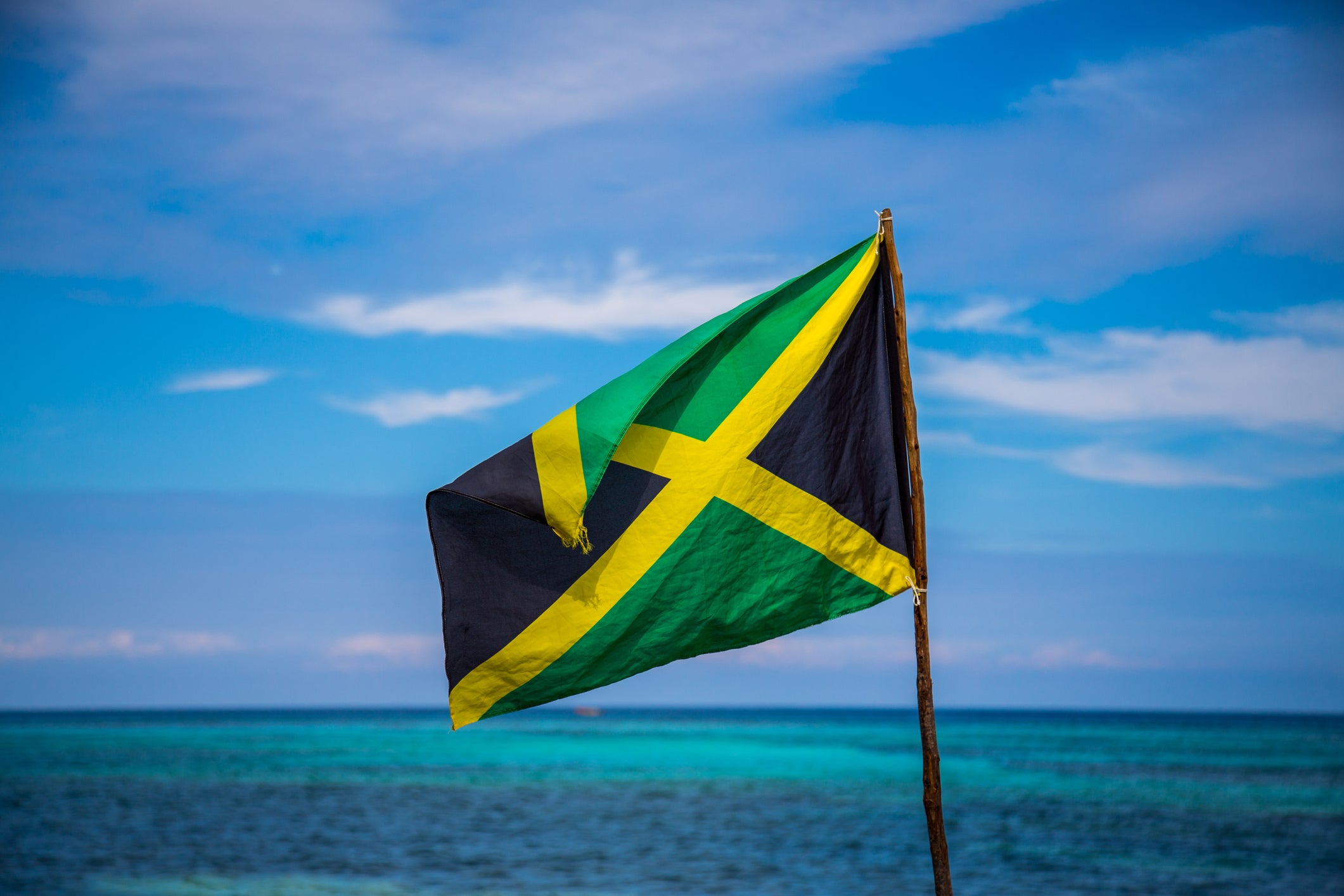 Jamaican flag and turquoise sea on sunny day