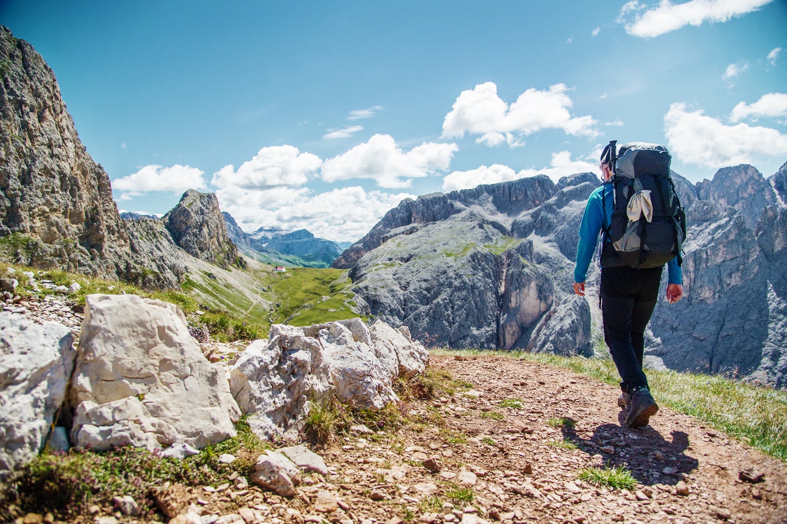Male hiker with rucksack walking on pathway in the Alps.