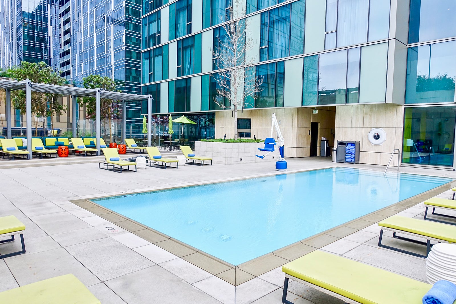 a hotel pool surrounded by lounge chairs with skyscrapers in the background