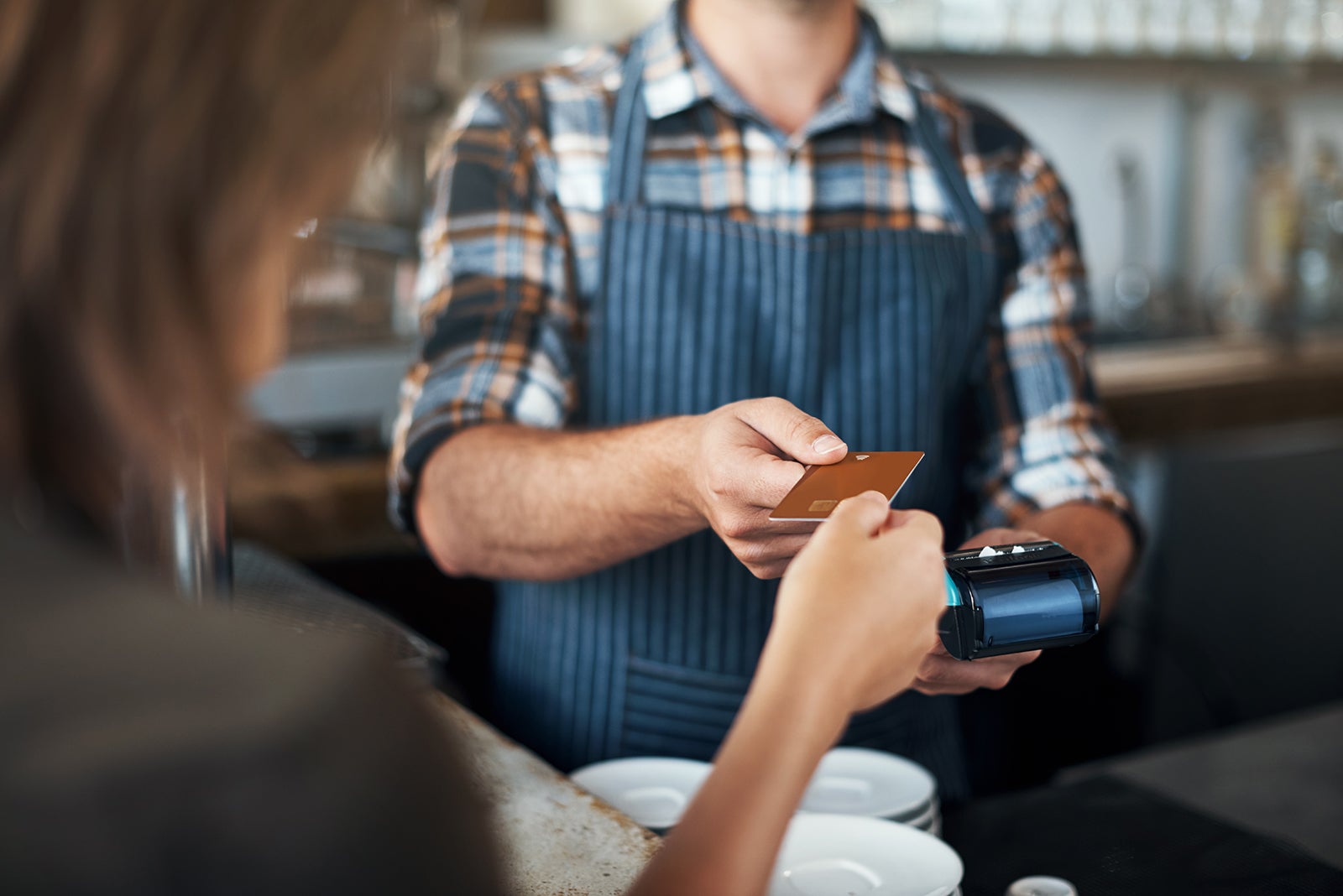 Closeup shot of a unrecognizable person giving a barman a credit card as payment inside of a restaurant