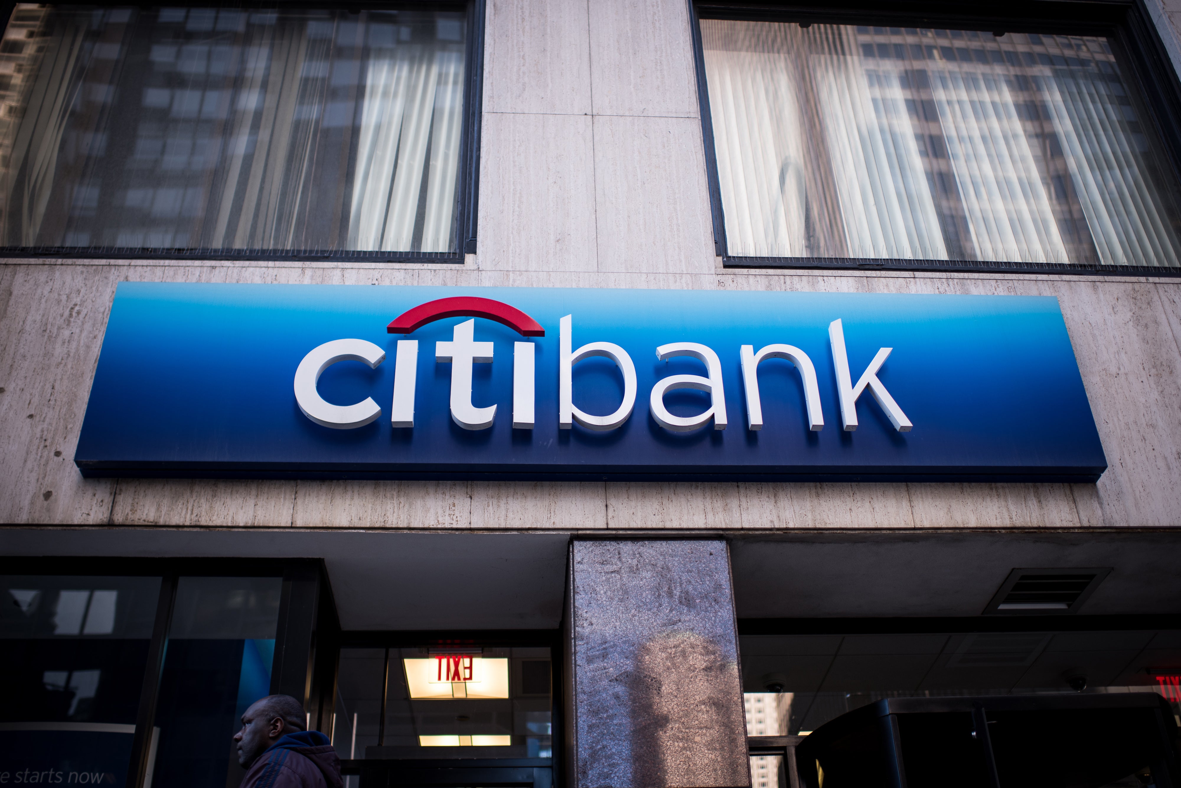 A man walks past a Citibank sign over an entrance