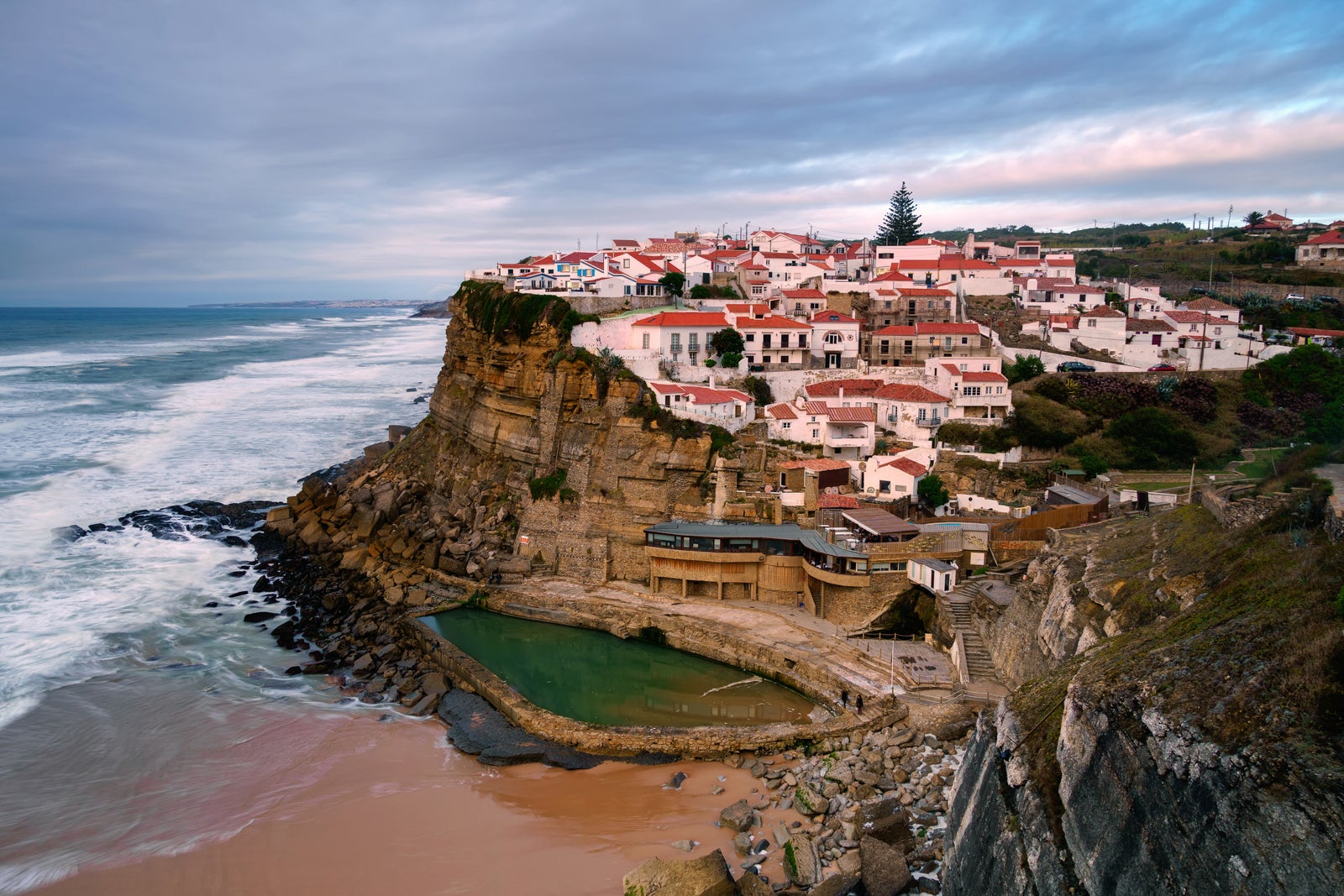 Typical village on the seaside cliff at sunset. Amazing seascape near Lisbon. Coastal landscape and tourist attraction of portugal. Sintra Natural Park.