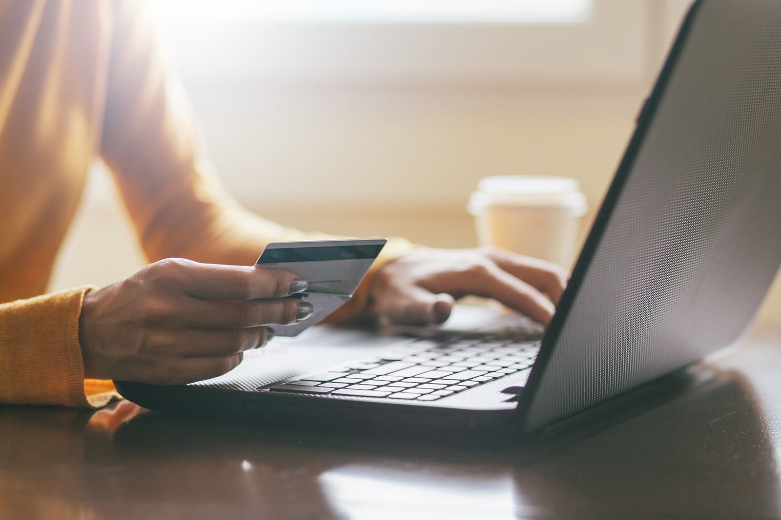 Hands holding credit card and coffee to go