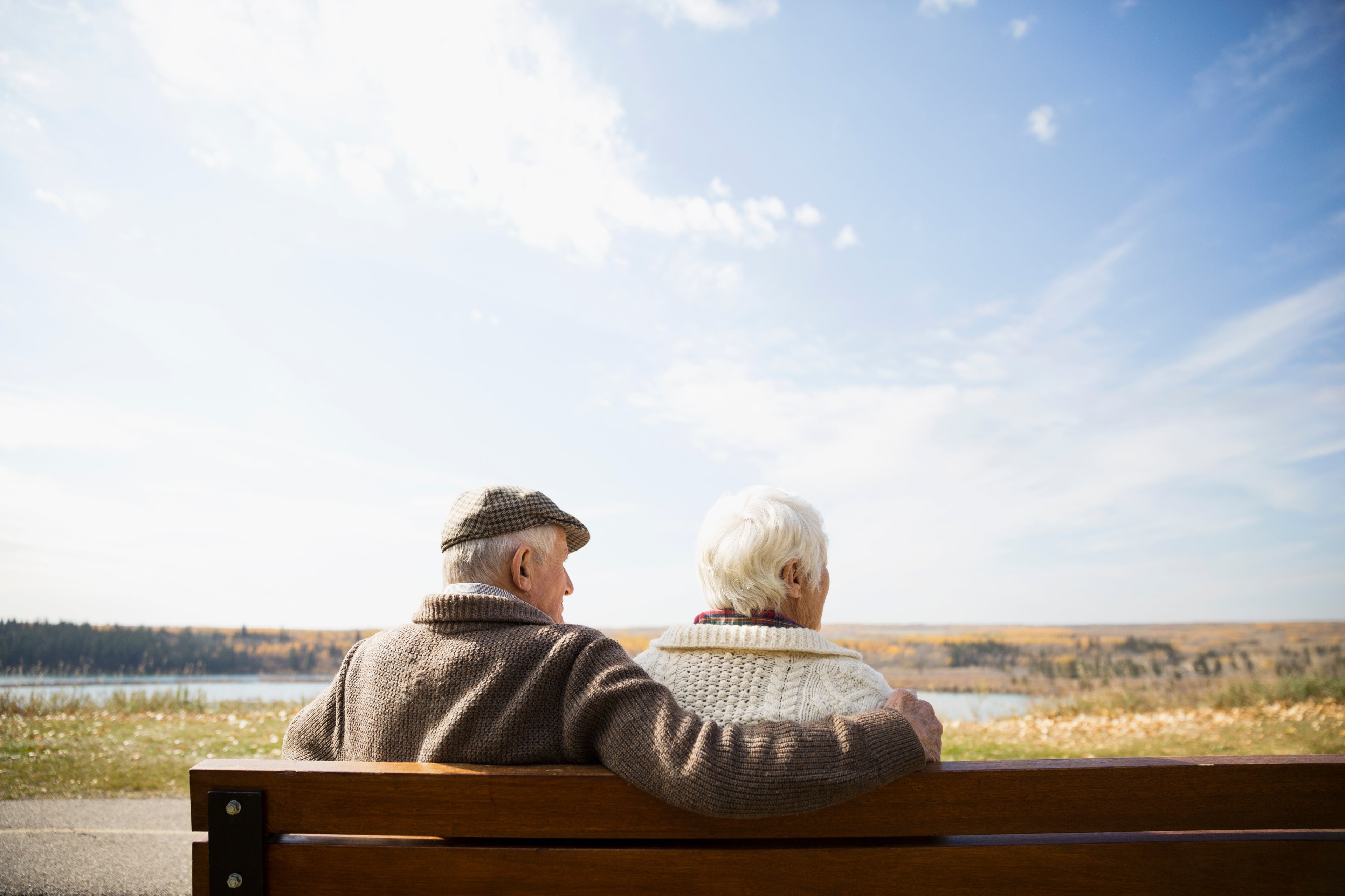 old persons travel card Senior couple sitting on bench looking at sunny autumn view