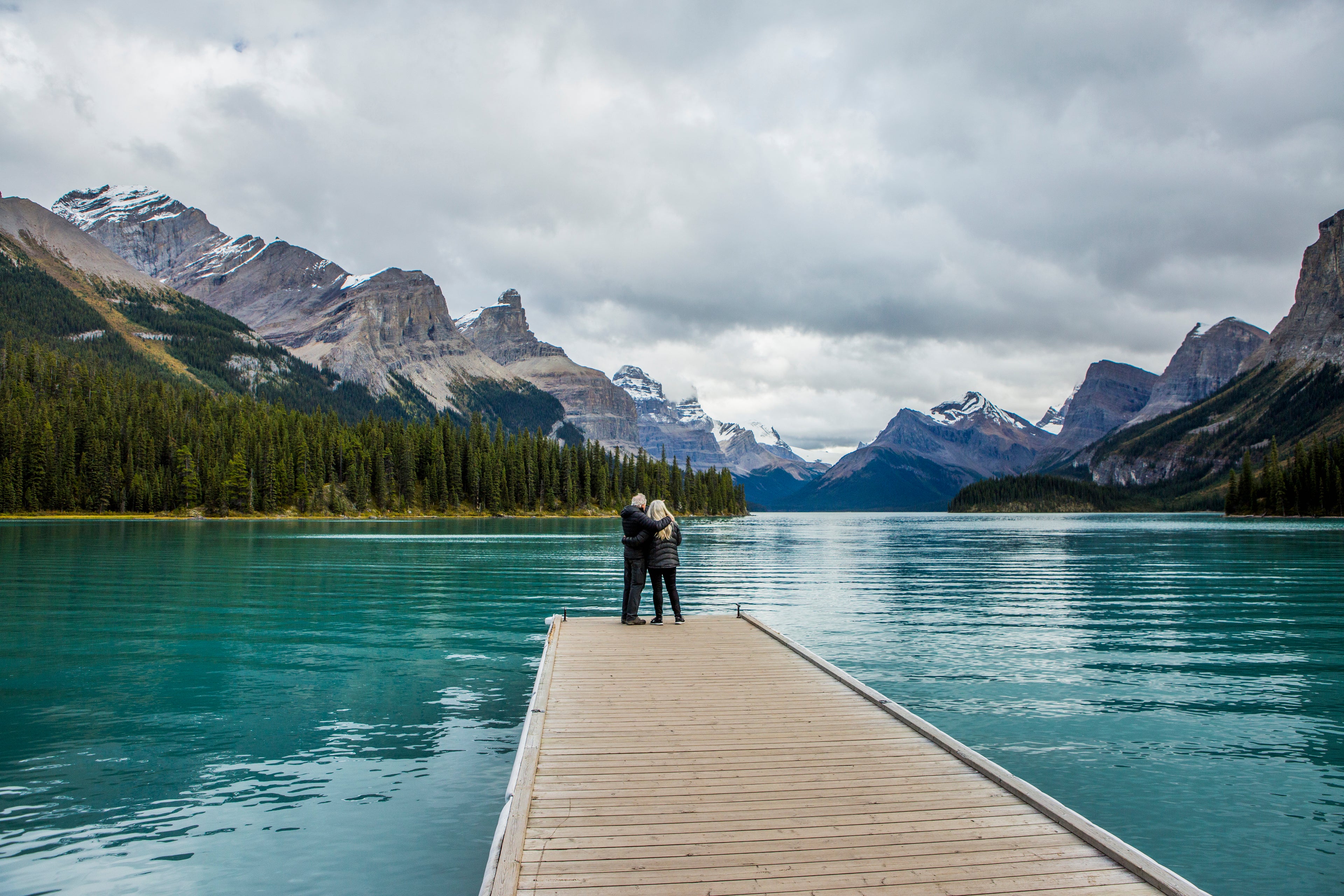 Caucasian couple standing at the end of dock on mountain lake