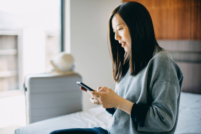 Young female traveller using smartphone in hotel room while on vacation