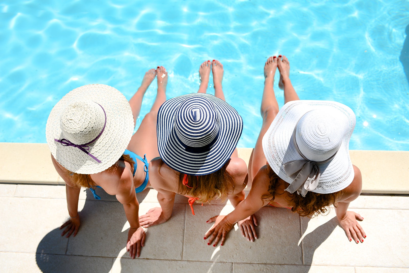 young woman sun hat sitting poolside resort pool summer holiday