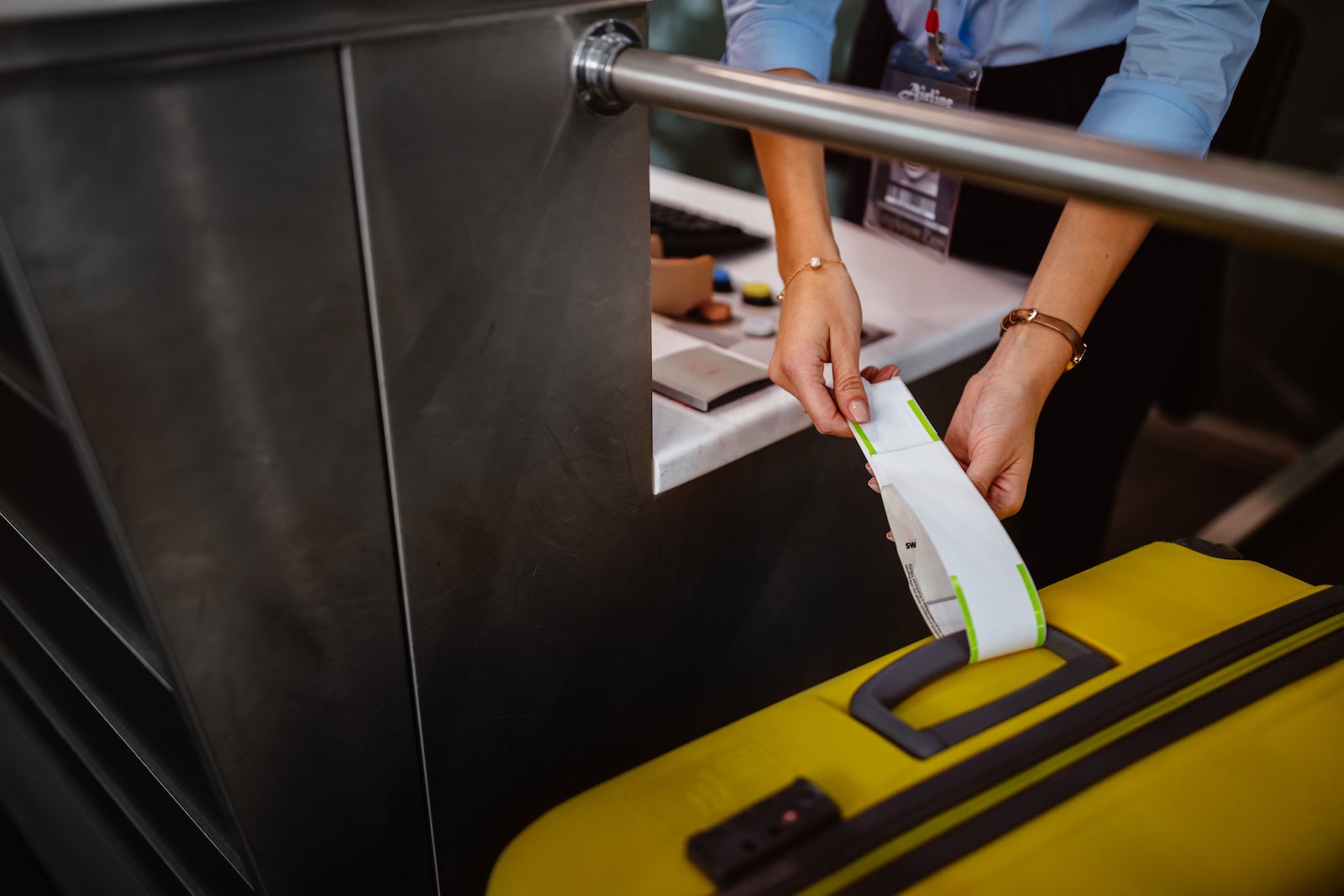Airport check-in counter employee attaching tag on luggage