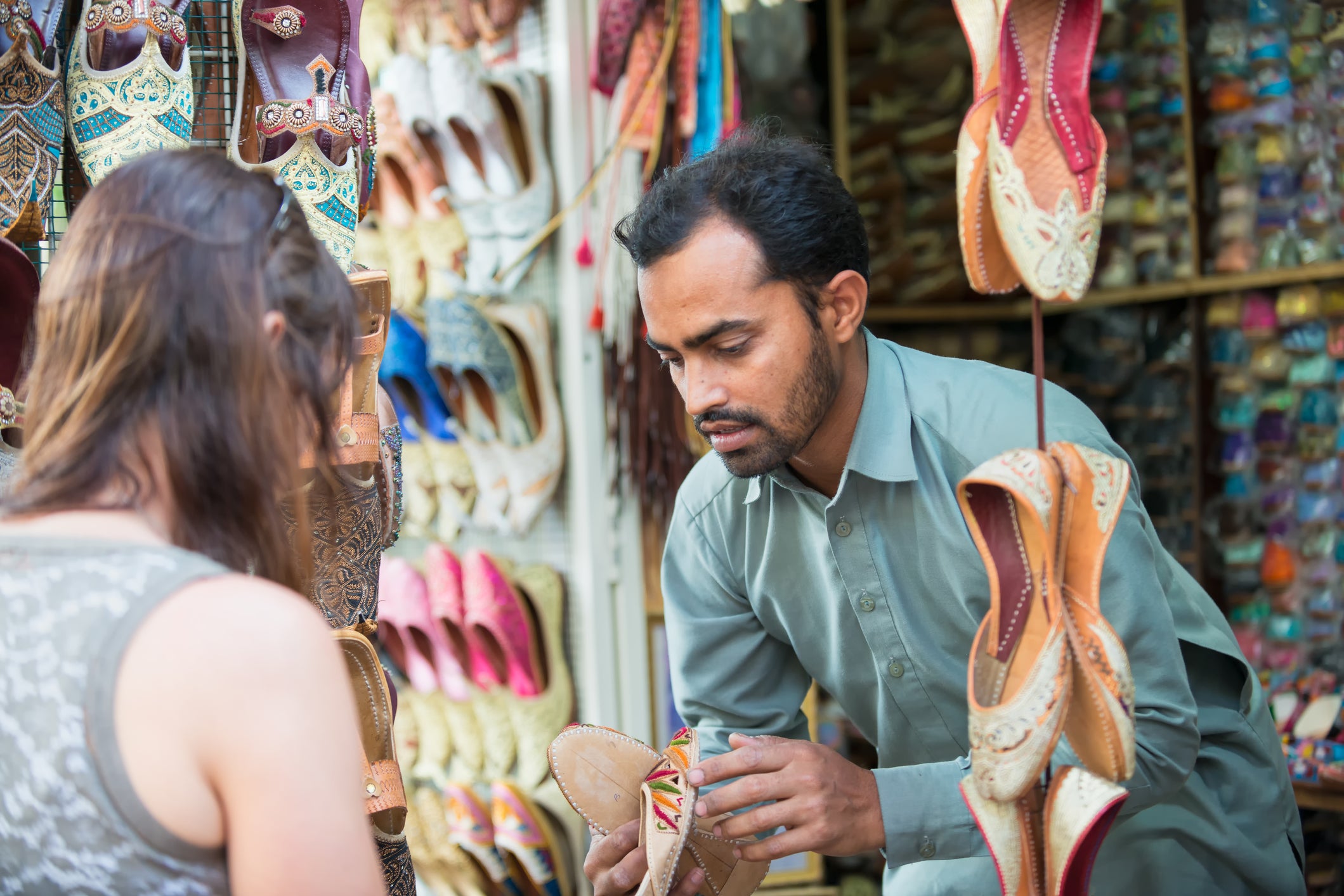 Salesman Showing Shoes to Woman Shopping at Souk, Dubai, UAE