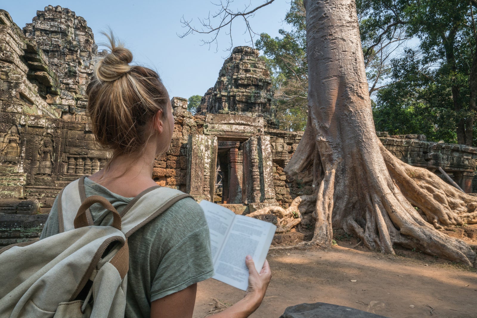 Young woman reading guidebook at ancient temple in Cambodia