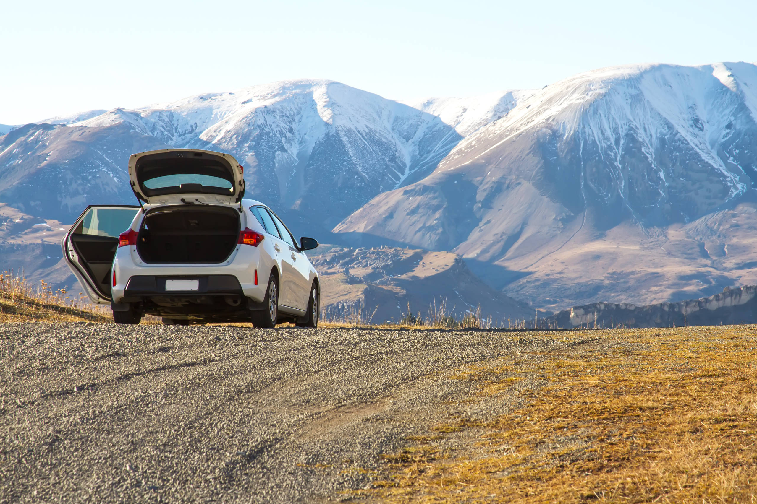 car on gravel road heading for mountains