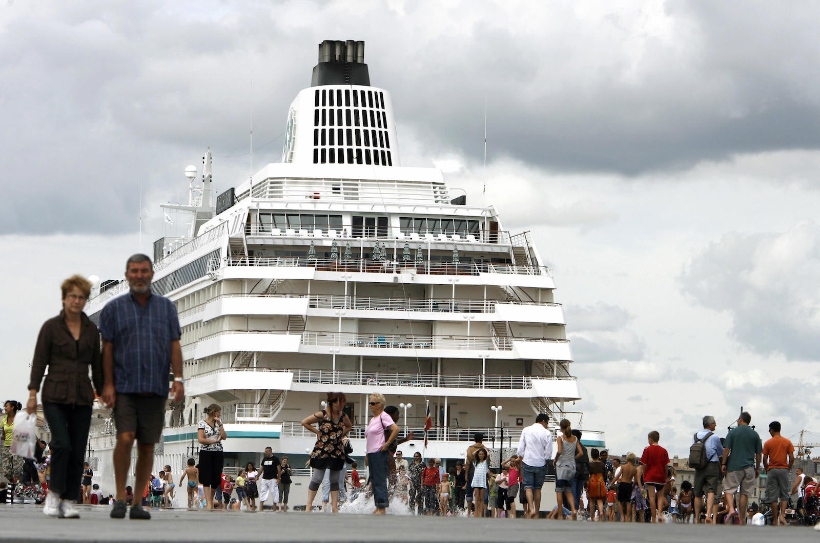 People walk past the tourist cruise ship