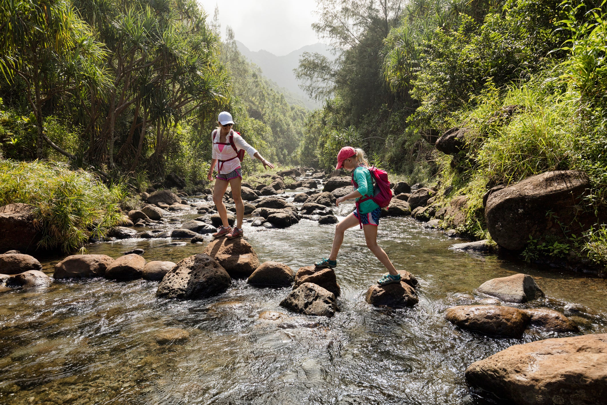 Mother and daughter crossing a creek, Kauai