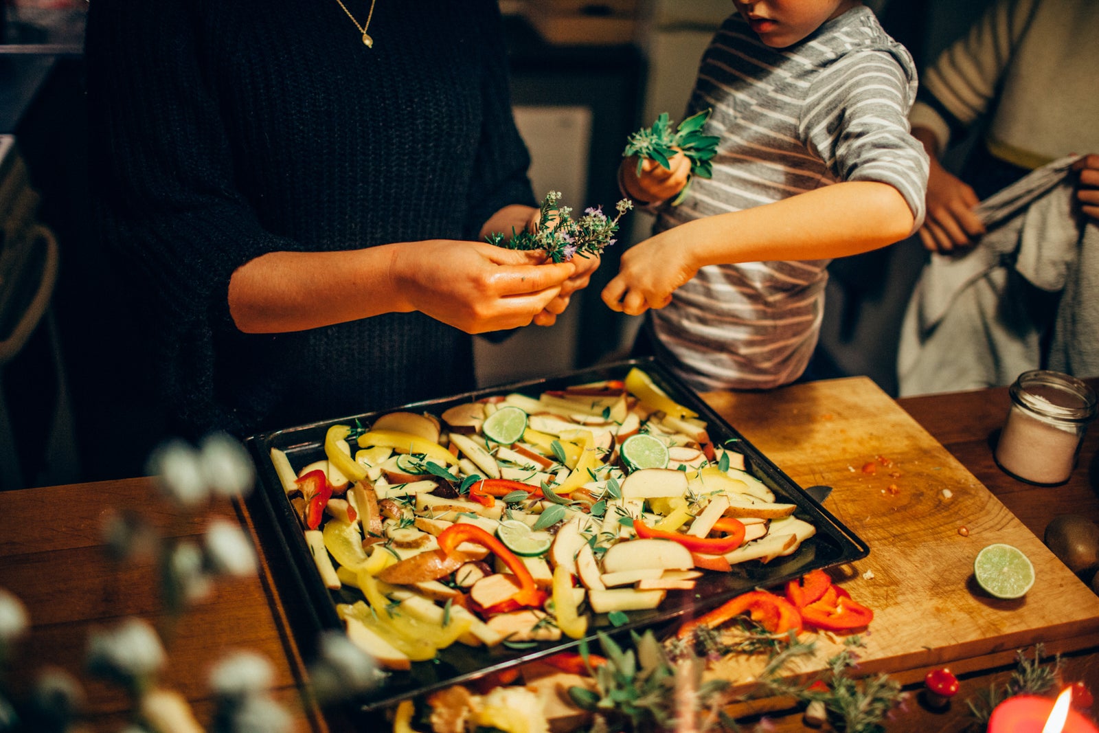 Young boy sprinkling fresh herbs on vegetable dish